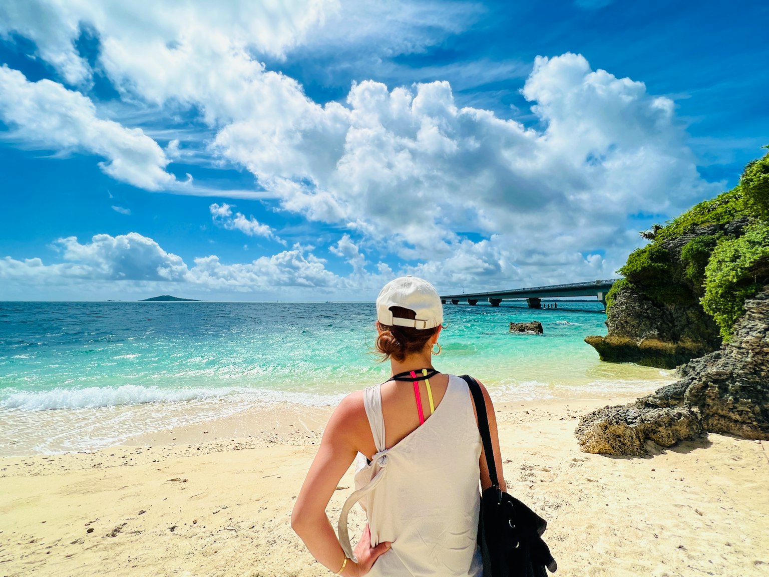 在海灘上凝視大海的女性 藍天和白雲 遠處可見橋