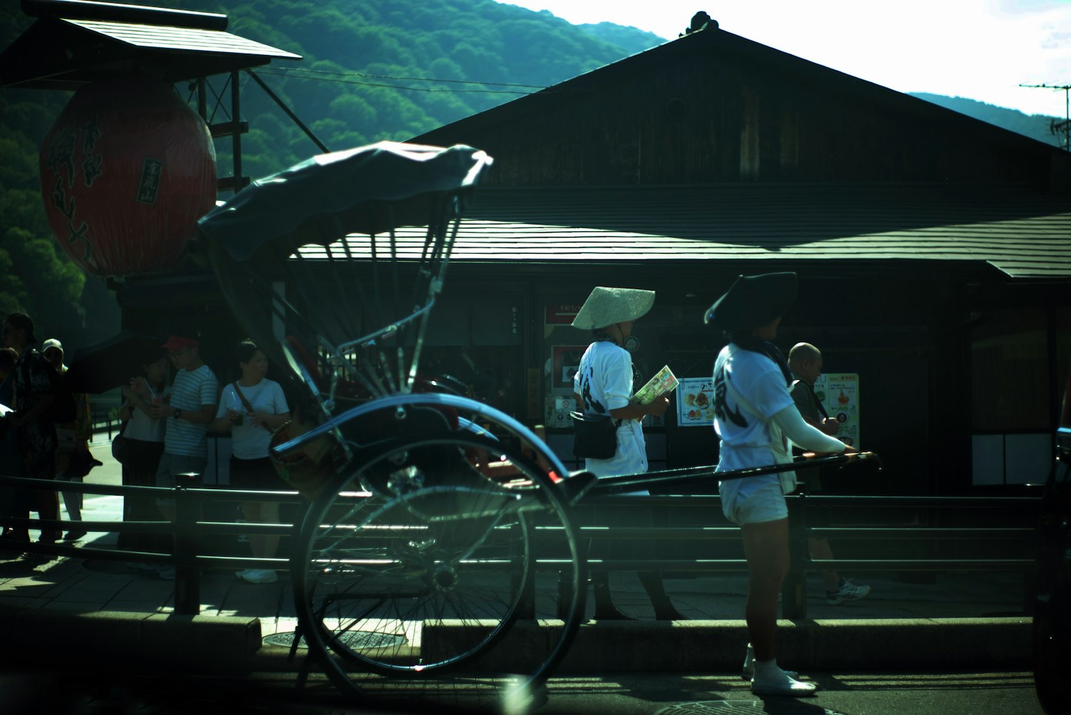 Rickshaw und Touristen in einer Landschaft mit Bergen und traditionellen Gebäuden im Hintergrund
