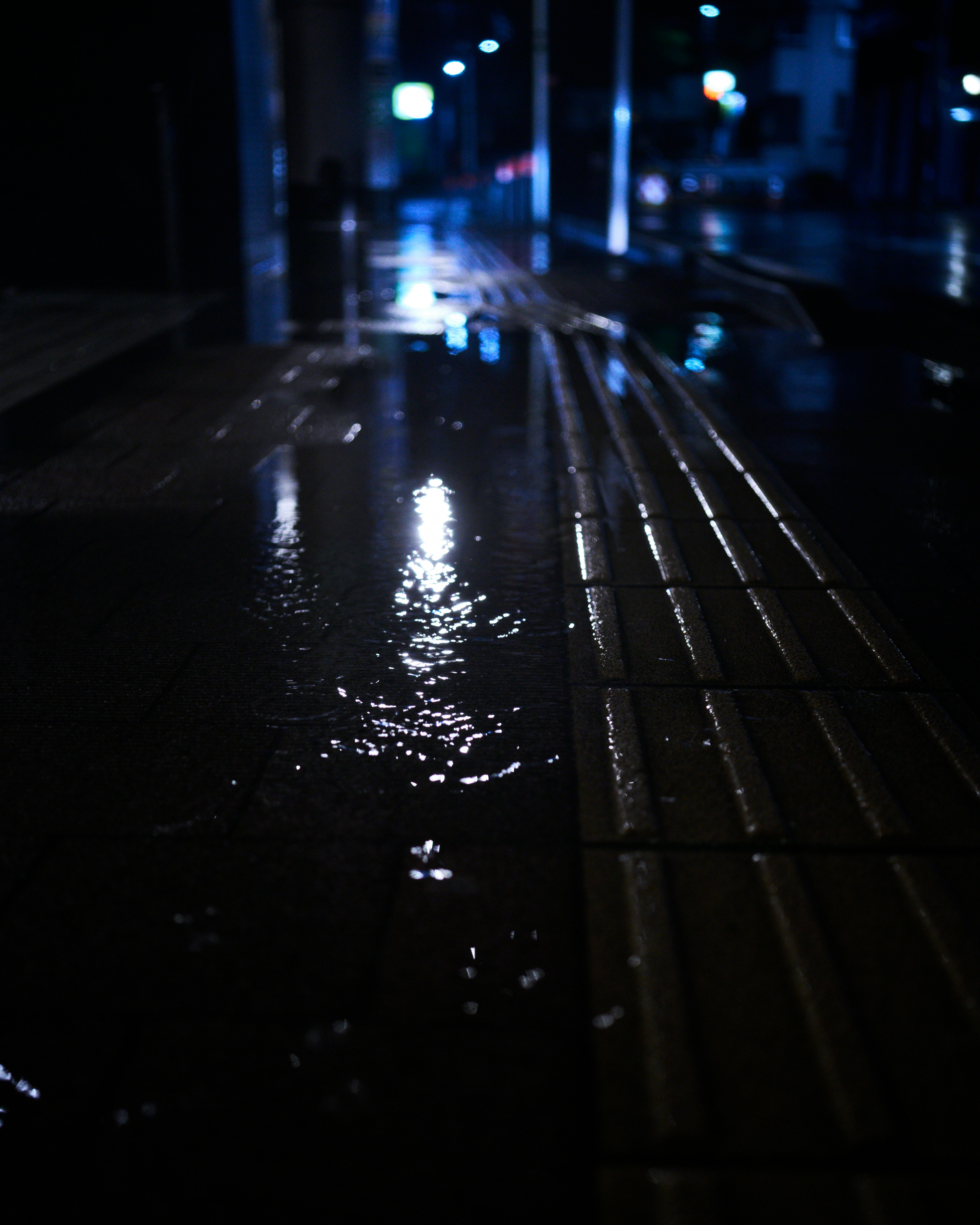 ถนนยามค่ำคืนหลังฝนตก พื้นถนนเปียกสะท้อนแสงไฟถนน