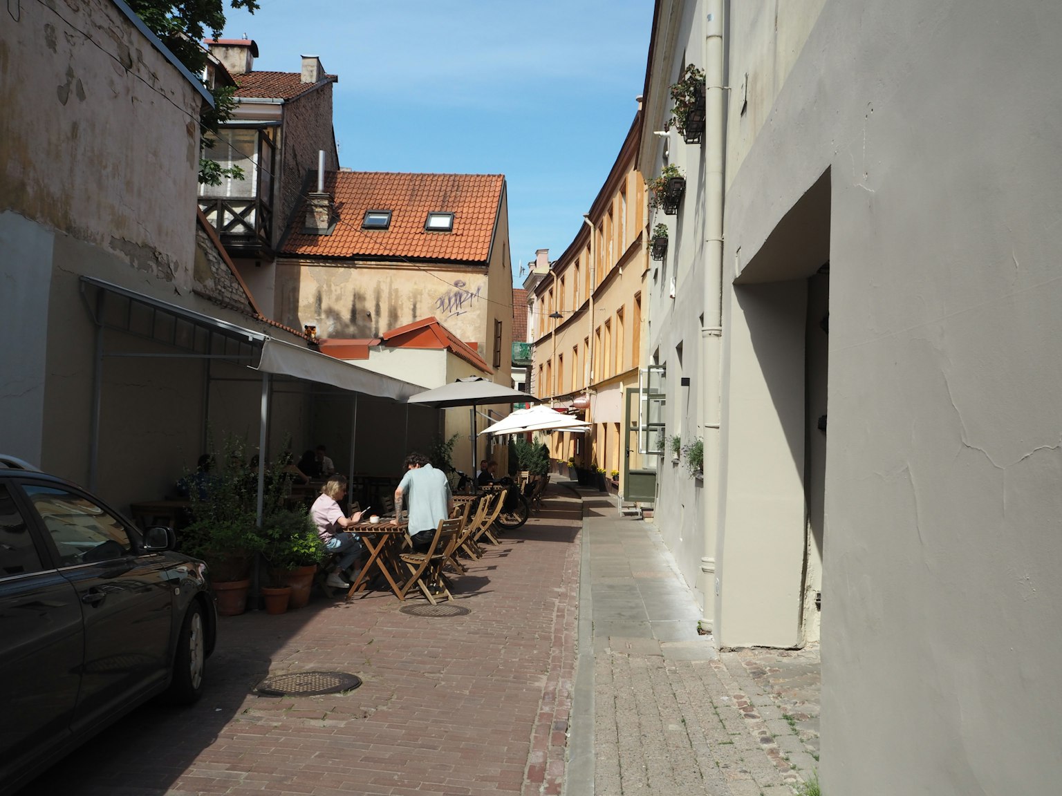 A narrow, winding street with outdoor café tables and chairs