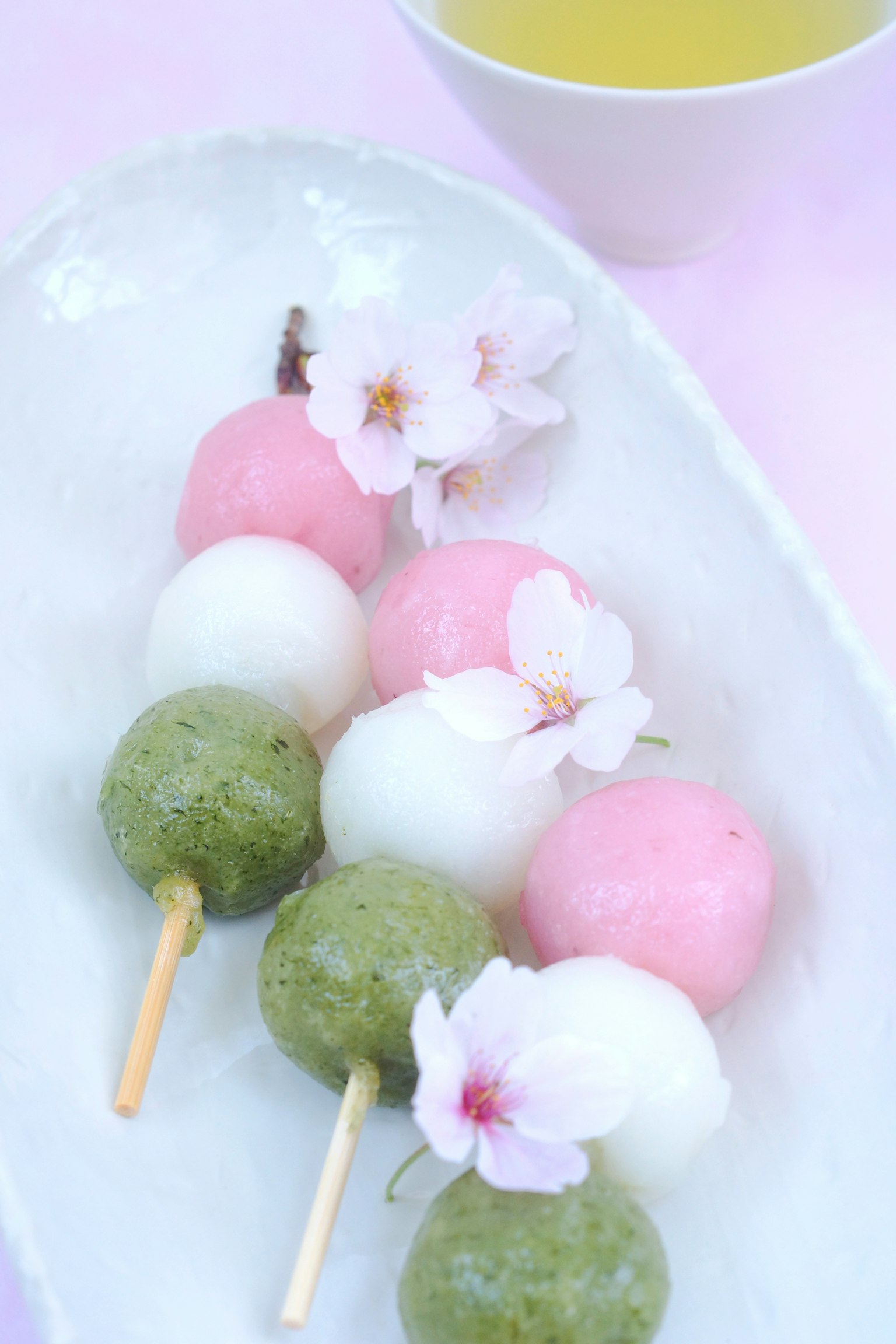 Bunte Dango-Spieße, geschmückt mit Kirschblüten auf einem weißen Teller