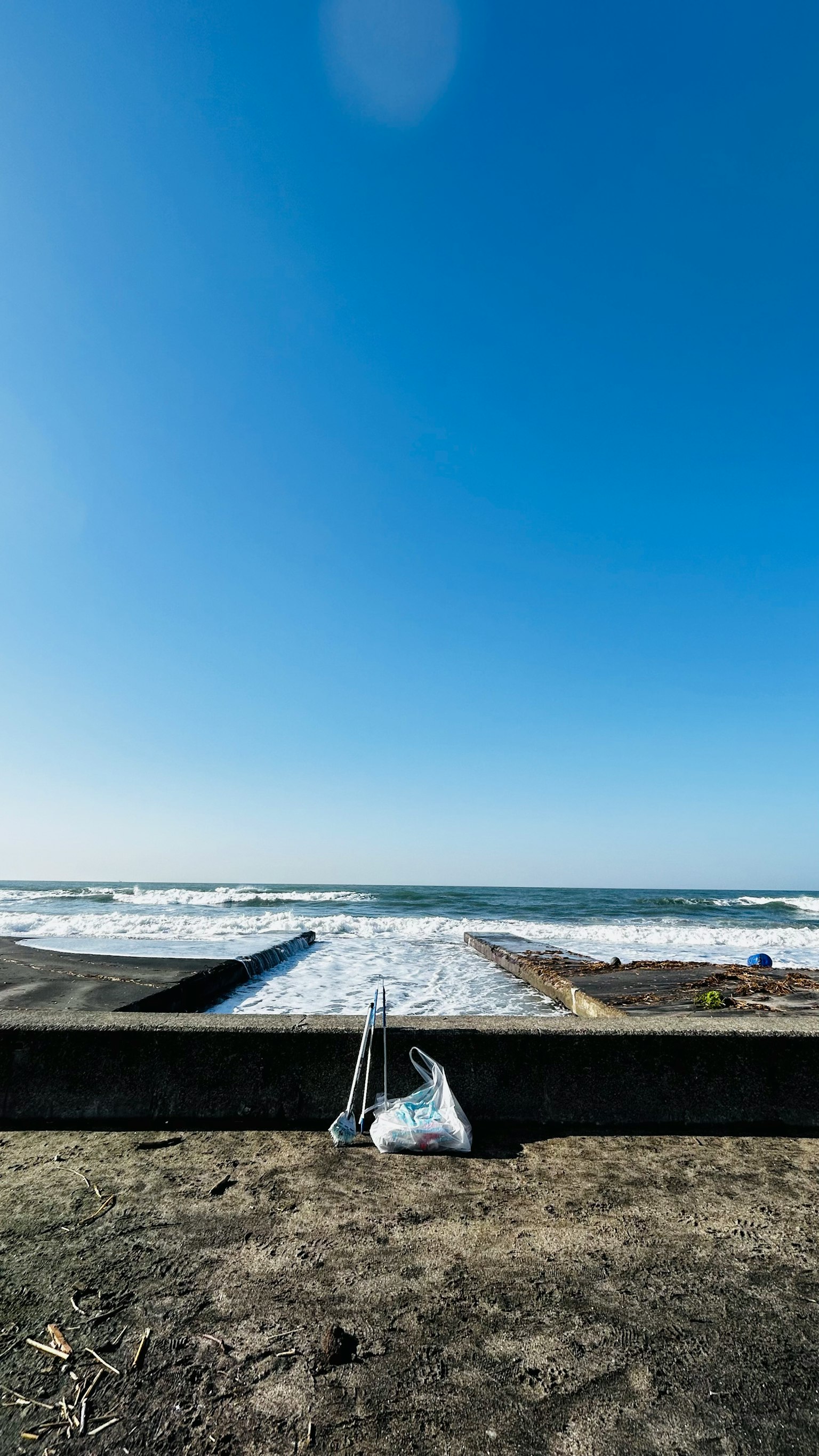 海灘場景藍天和海浪混凝土牆沙灘上的包