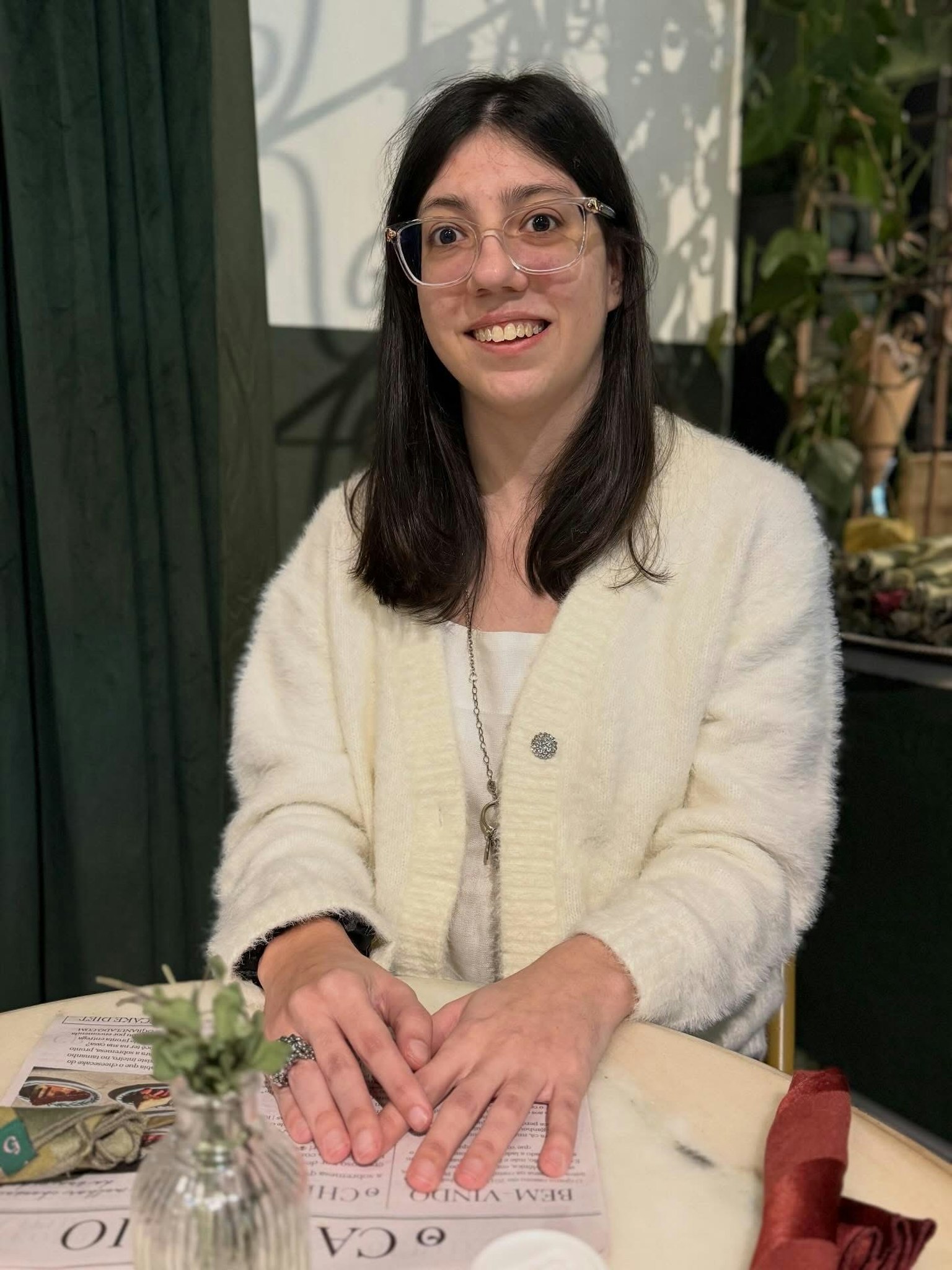 カジュアルな白いセーターを着た女性がテーブルに座っている