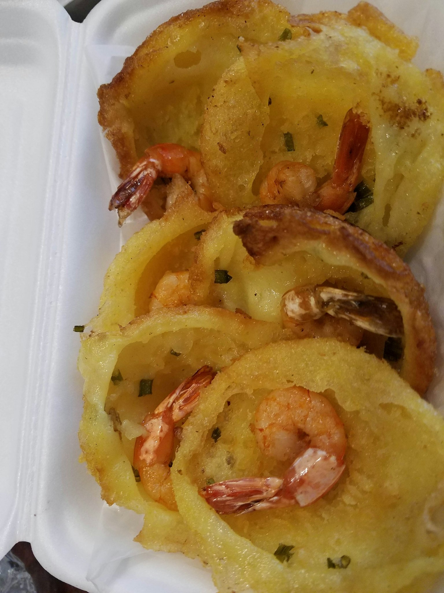 Piatto di gamberi e patate arrosto servito in un contenitore bianco