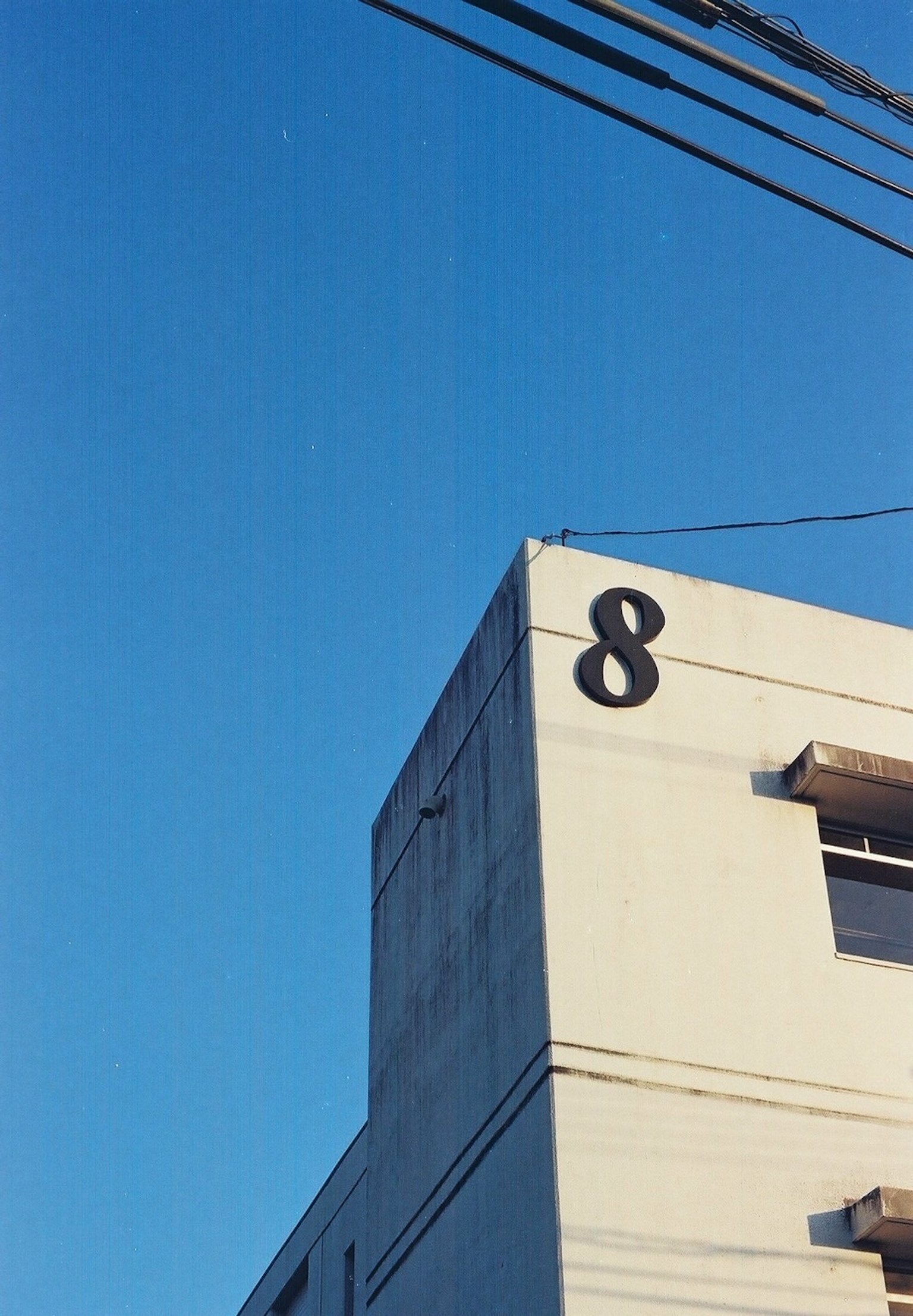 Un angolo di un edificio bianco con un grande numero 8 sotto un cielo blu