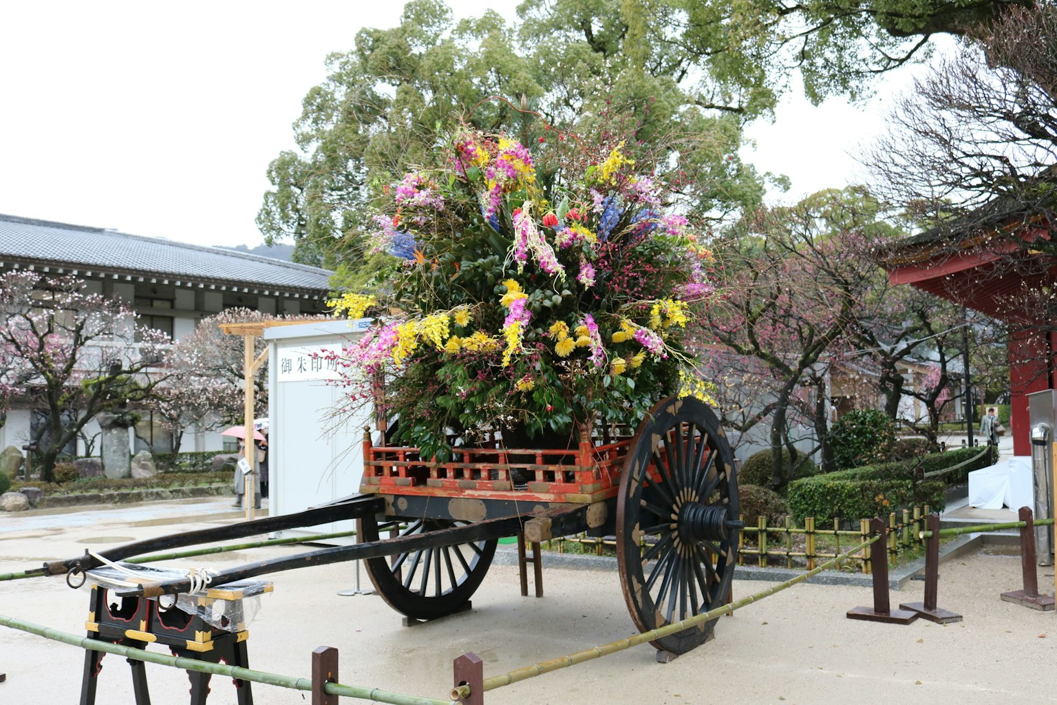 Traditioneller japanischer Wagen, geschmückt mit bunten Blumen und Kirschbäumen im Hintergrund