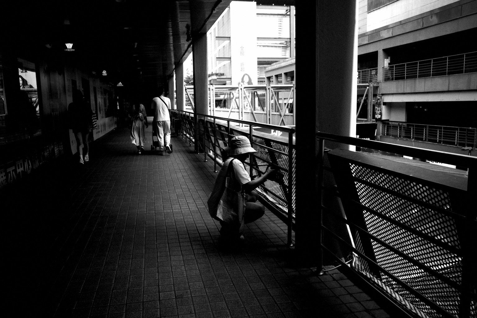 黒と白のトンネルの中で、男性が手すりに寄りかかっている