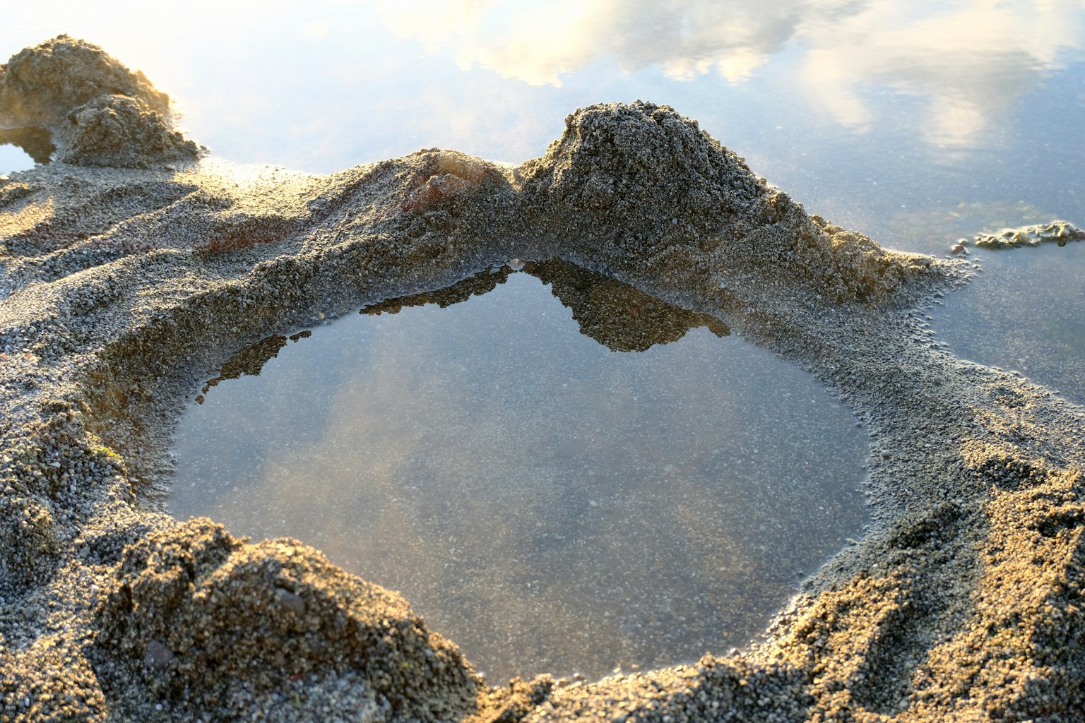 Imagen que captura un charco de agua en terreno arenoso con texturas únicas