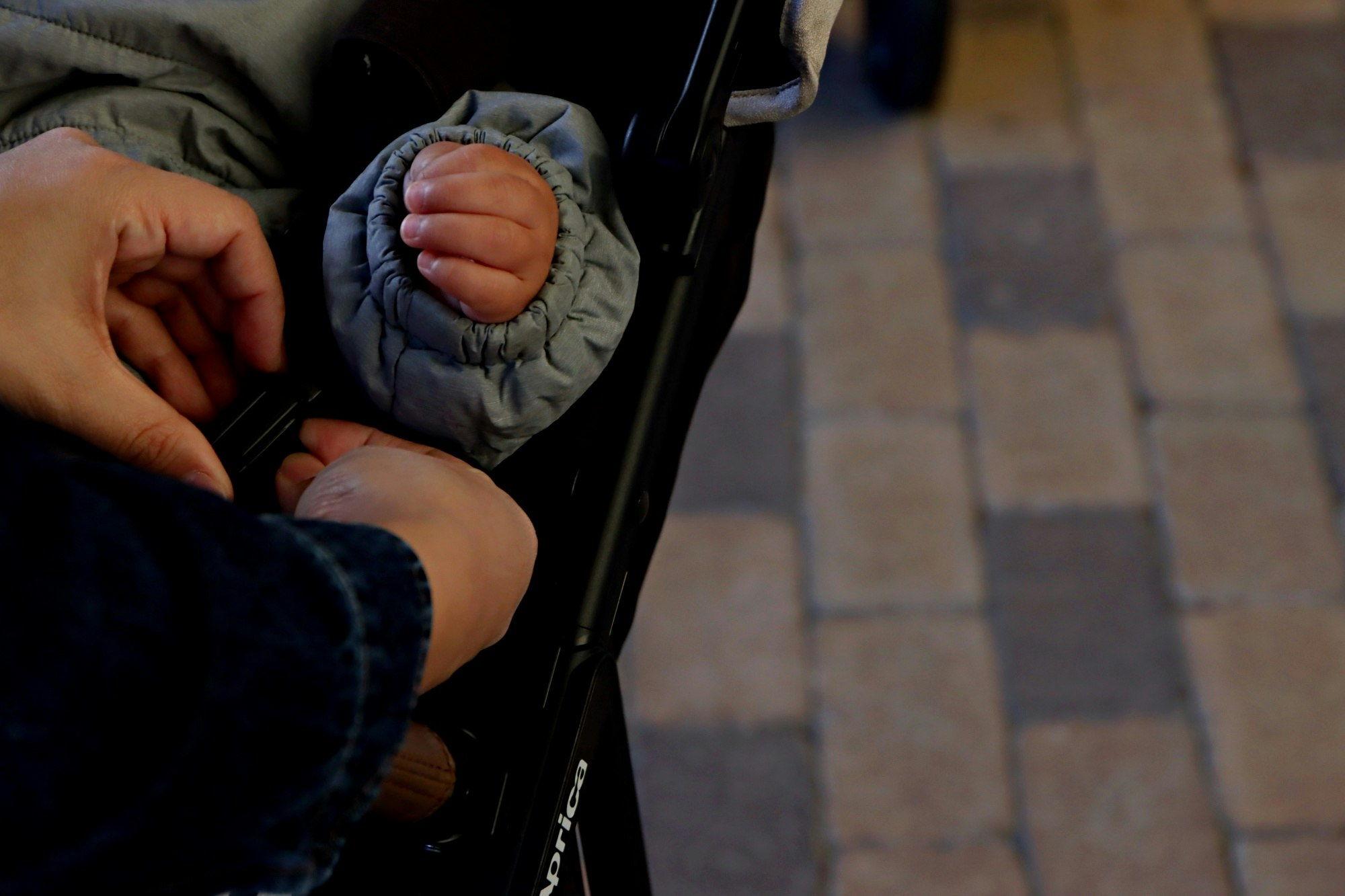 baby in a stroller with an adult’s hand nearby