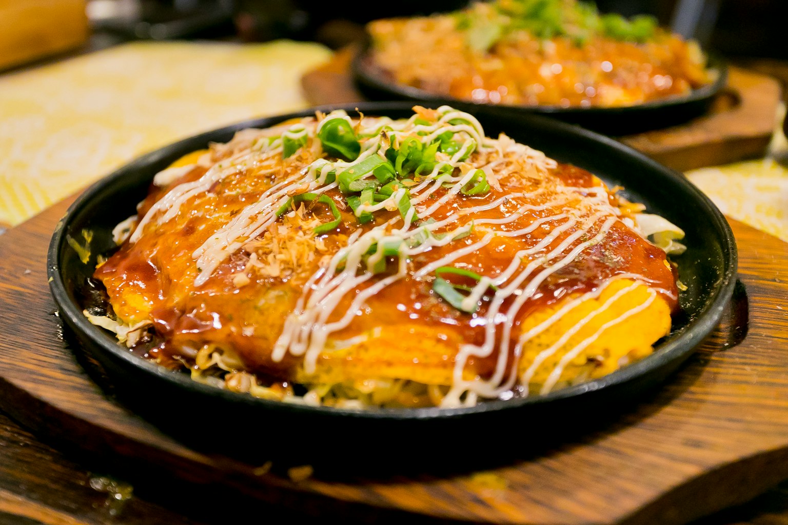 Sizzling plate of omurice topped with sauce and mayonnaise garnished with scallions