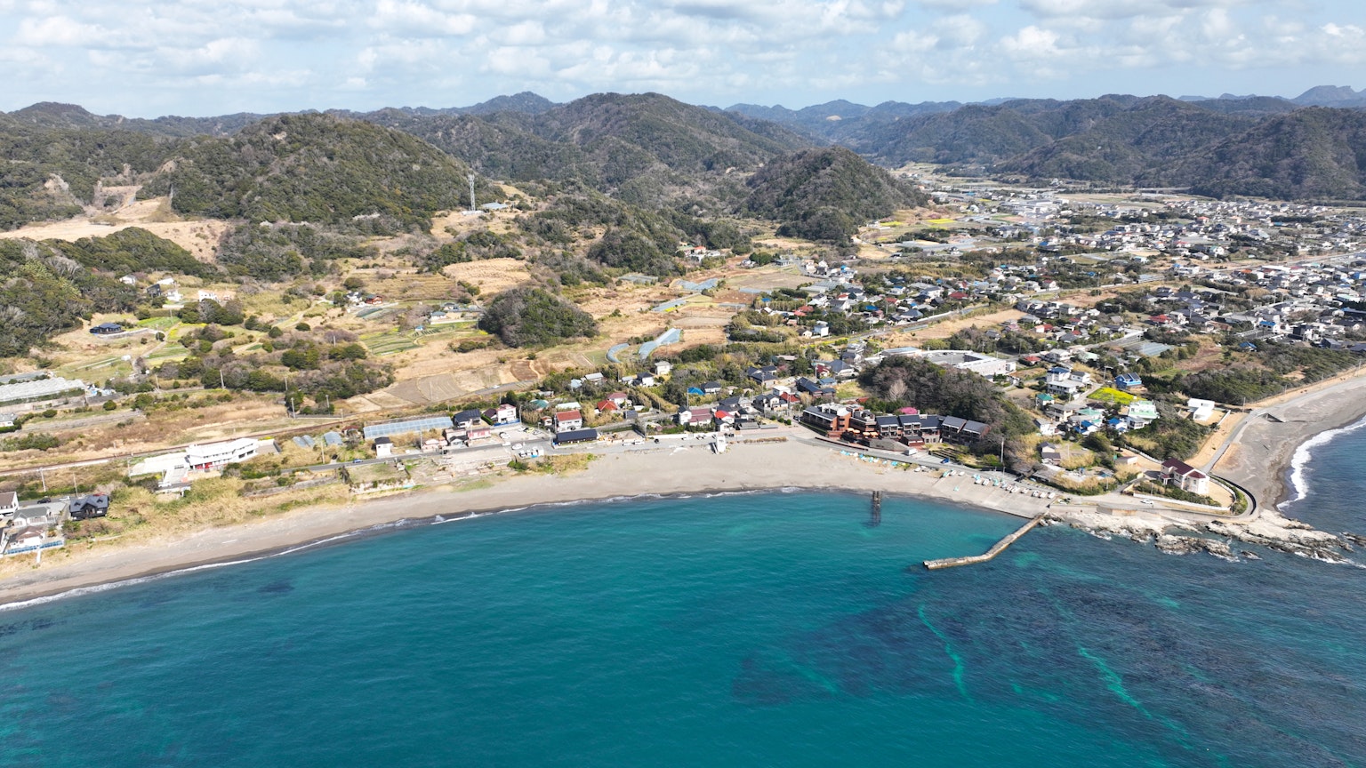 海岸城鎮的航拍圖，藍色海洋和丘陵