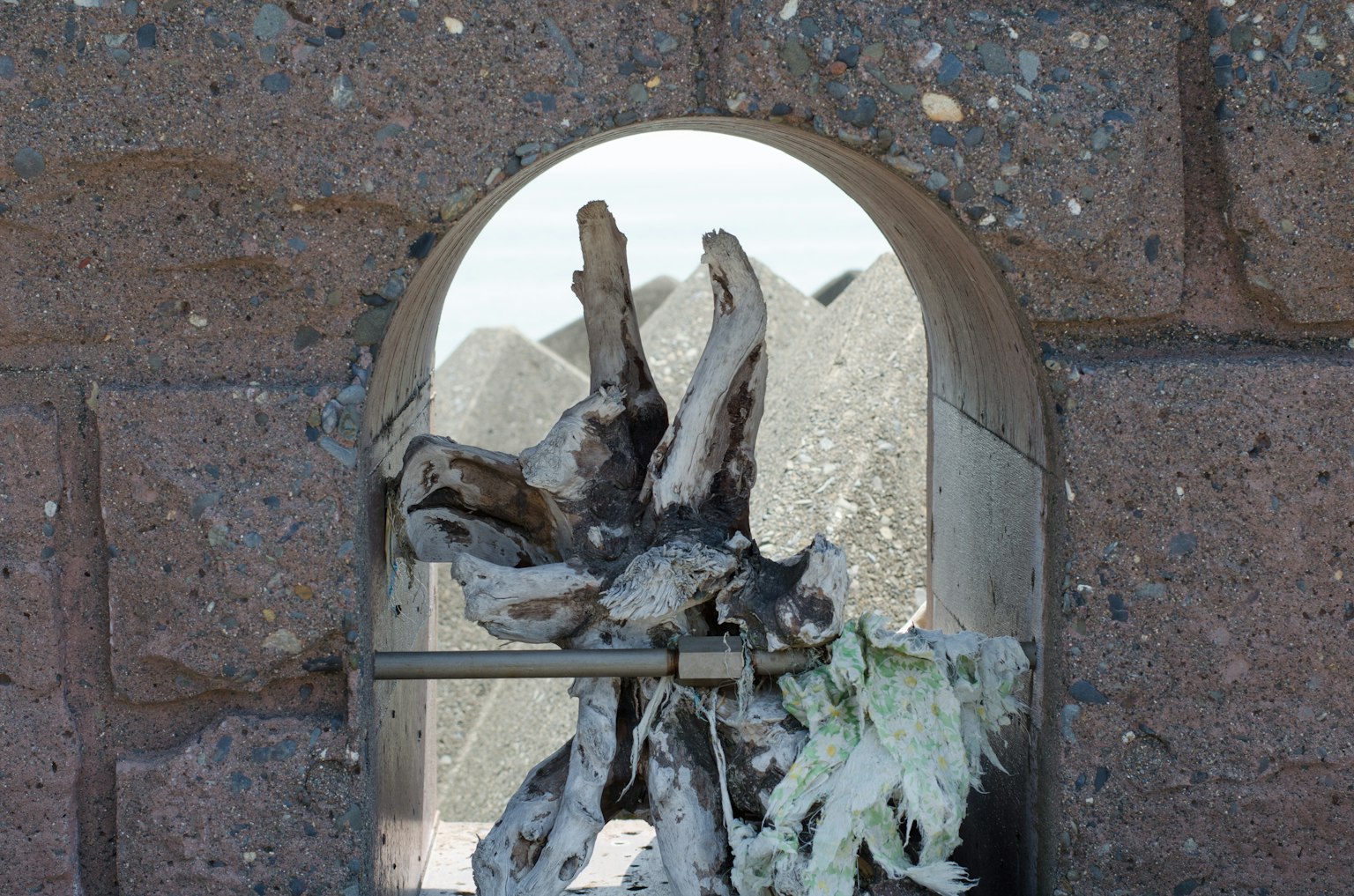 Scultura in legno vista attraverso una finestra ad arco con montagne sullo sfondo