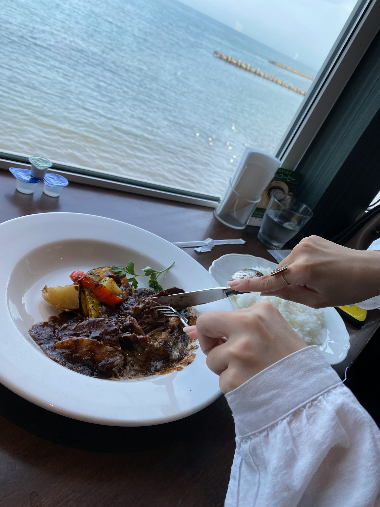 海景用餐场景 人正在用刀叉切肉菜