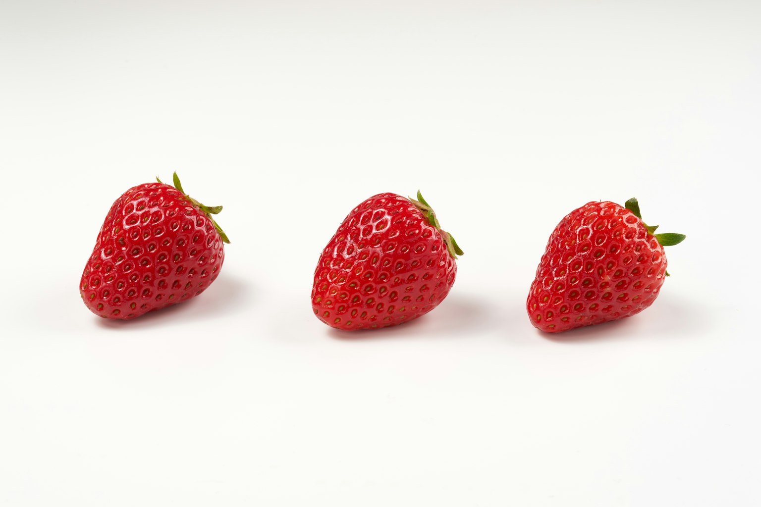 Drei frische Erdbeeren auf einem weißen Hintergrund angeordnet