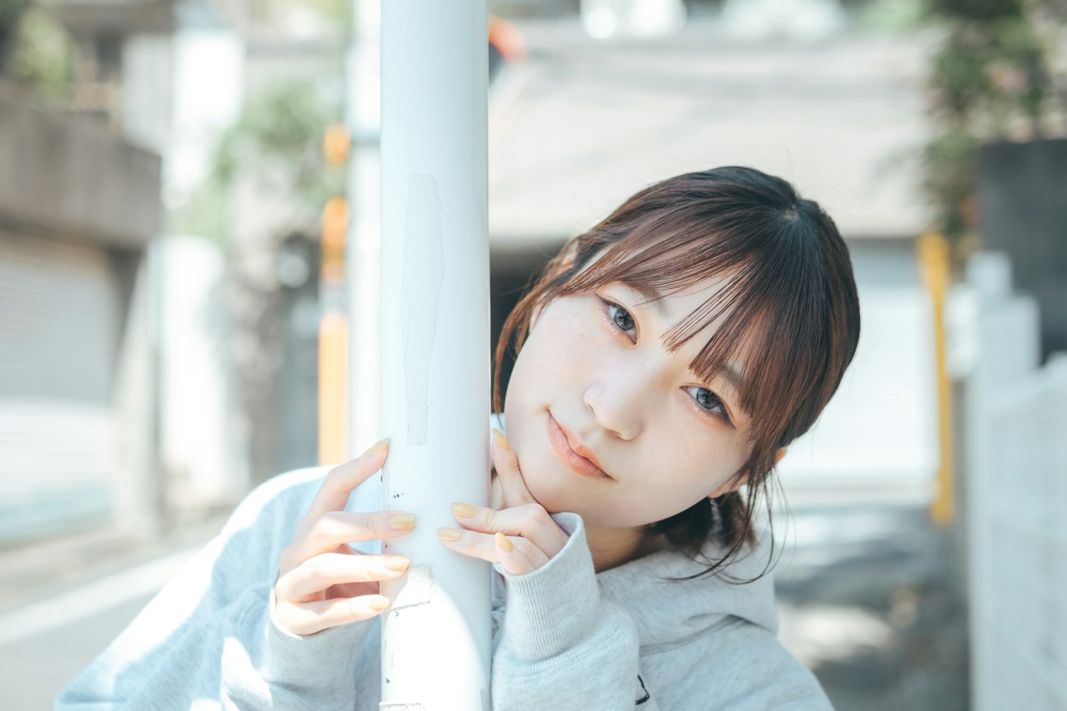 一位女性在街上靠著柱子的肖像，溫柔的表情和自然光
