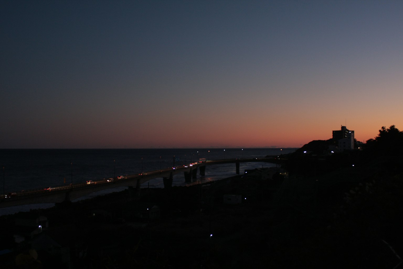 Coastal view at dusk with lights along the bridge
