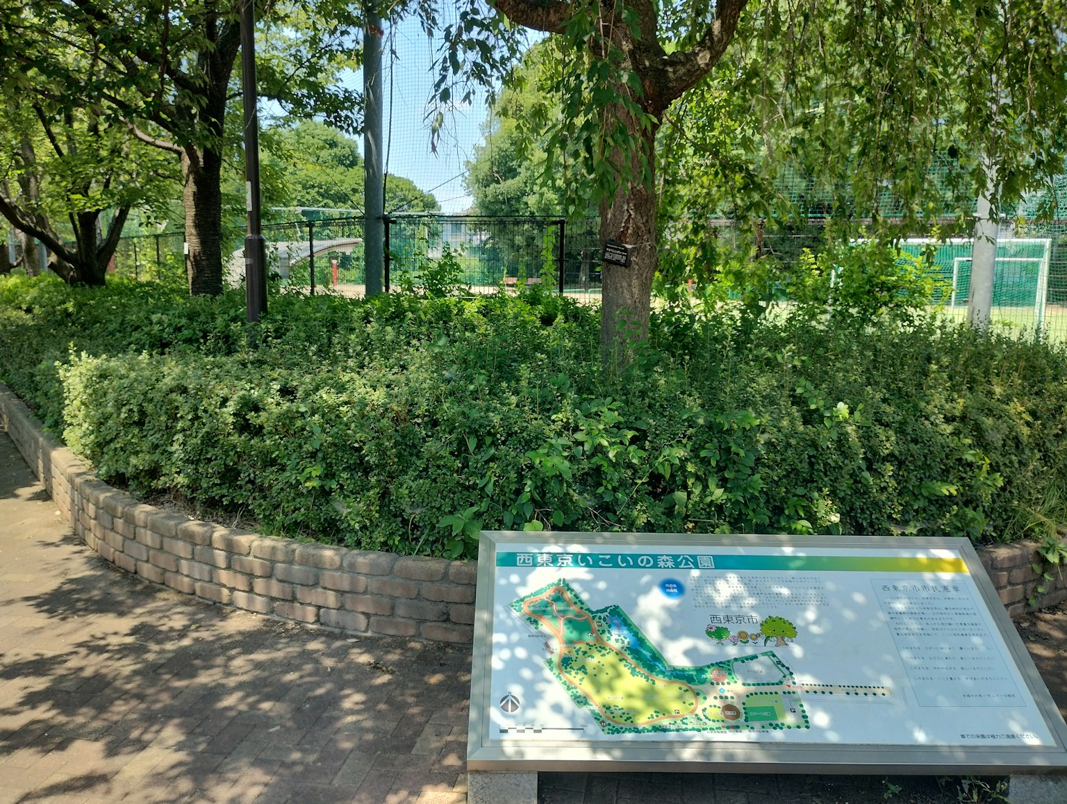 Ein grüner Bereich in einem Park mit einem Kartenzeichen umgeben von Bäumen und Sträuchern