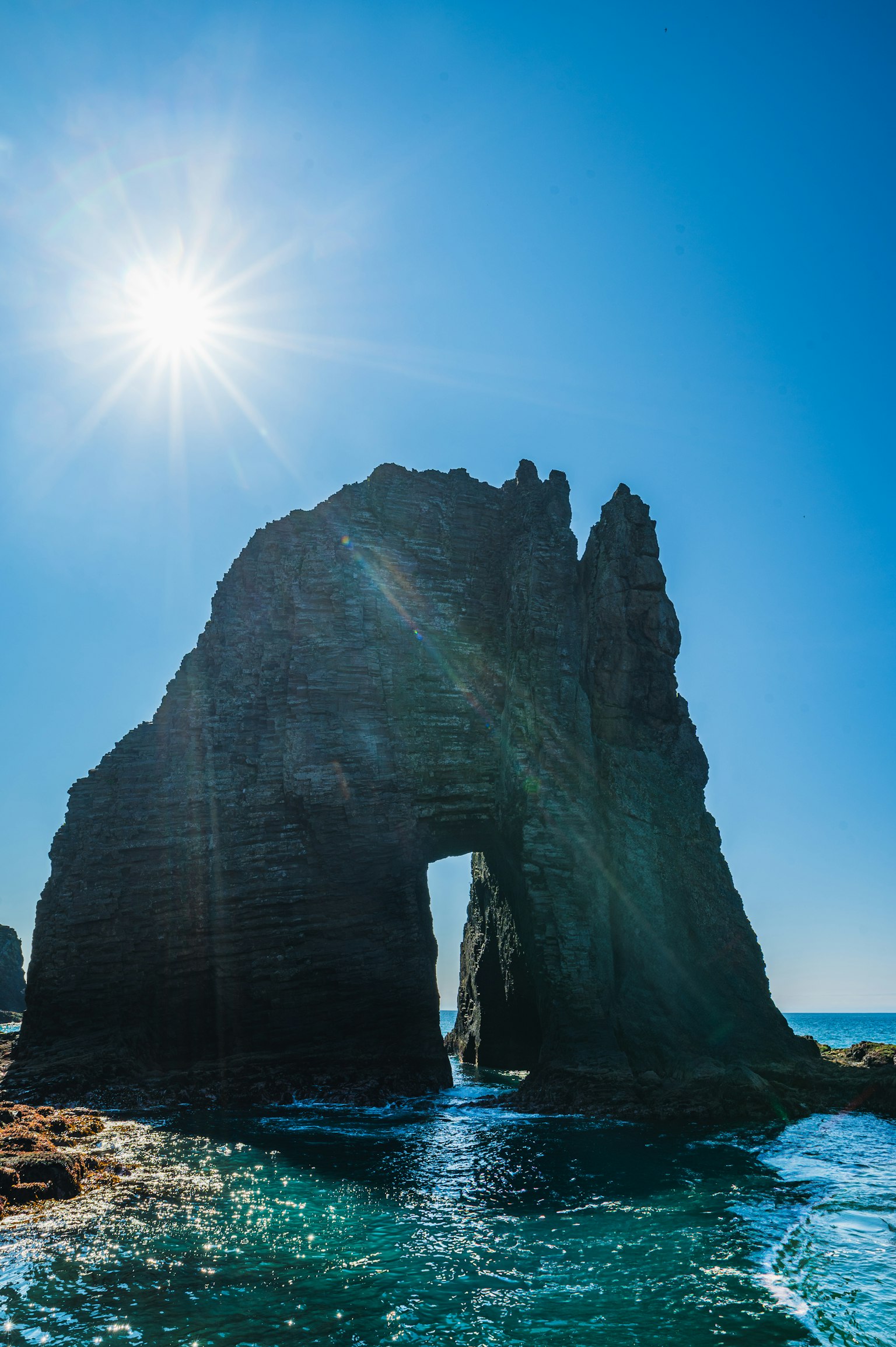 Grande arco di roccia vicino al mare con sole brillante