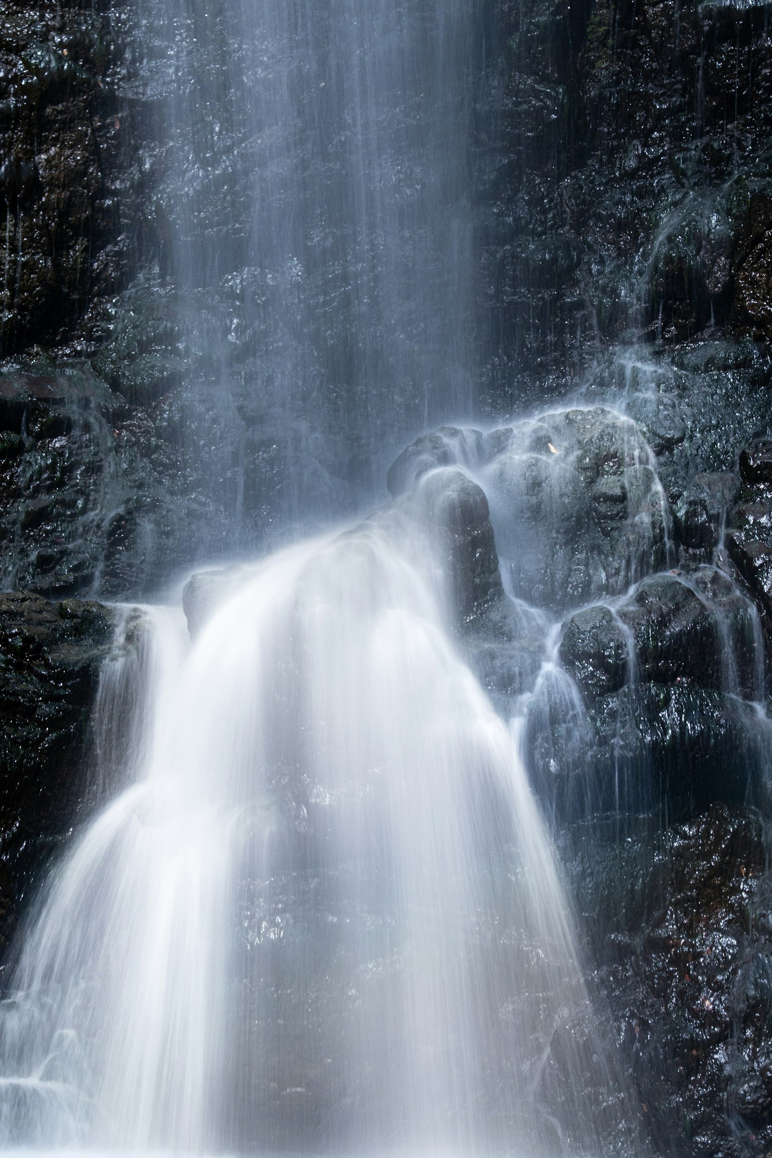 Imagen de una cascada que cae sobre rocas La claridad del agua y la textura de las rocas son prominentes