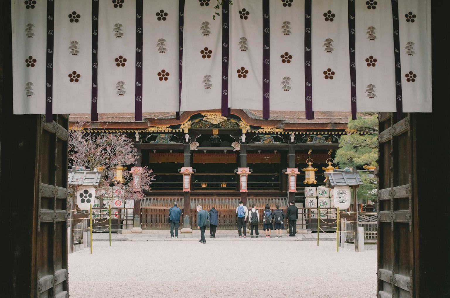 View of worshippers and traditional decorations from a shrine gate