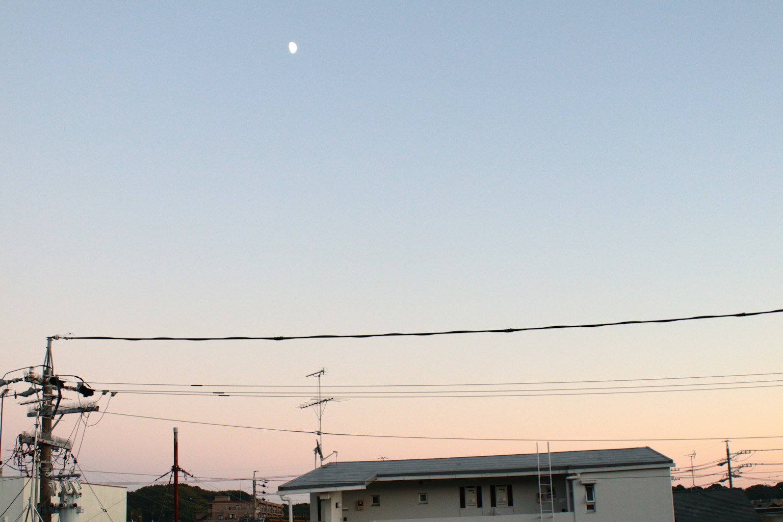 Cielo crepuscular con luna visible y un área residencial