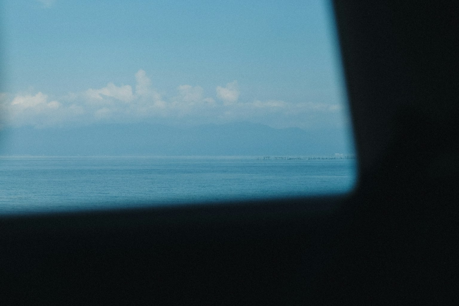 View of blue sea and clouds seen through a window