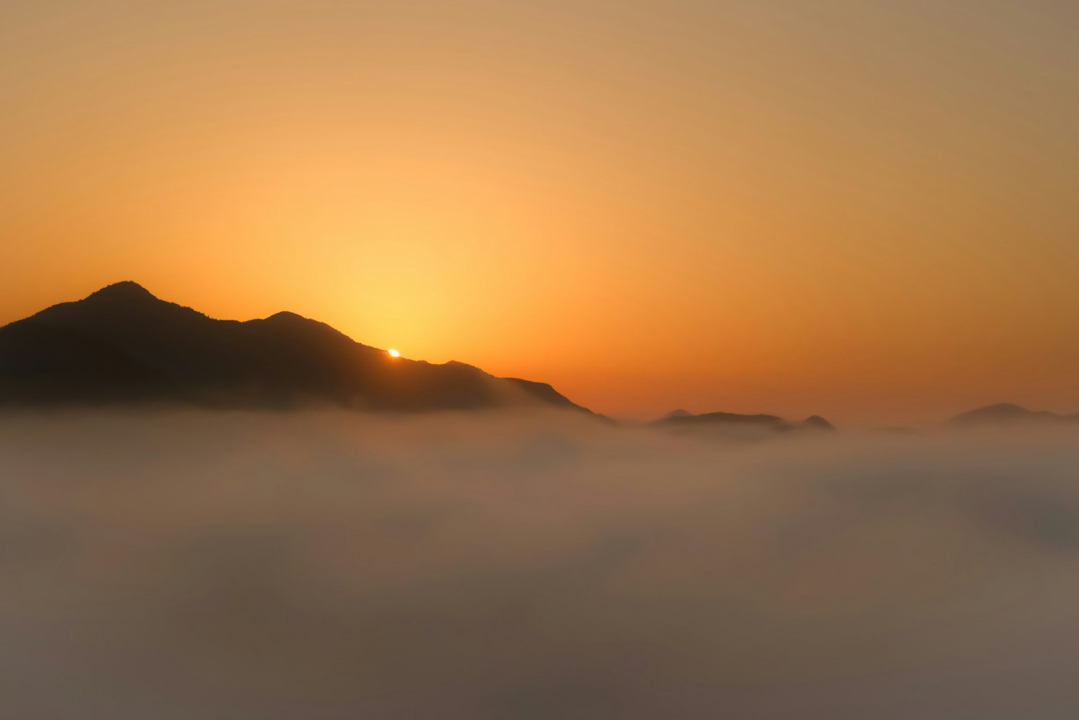 Montagnes enveloppées de brouillard avec un soleil levant