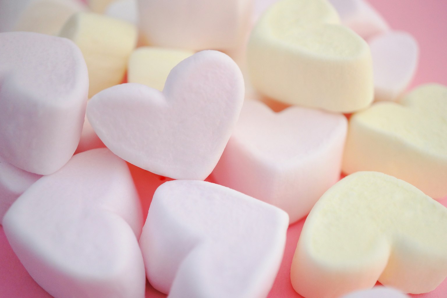 心形棉花糖散落在粉色背景上