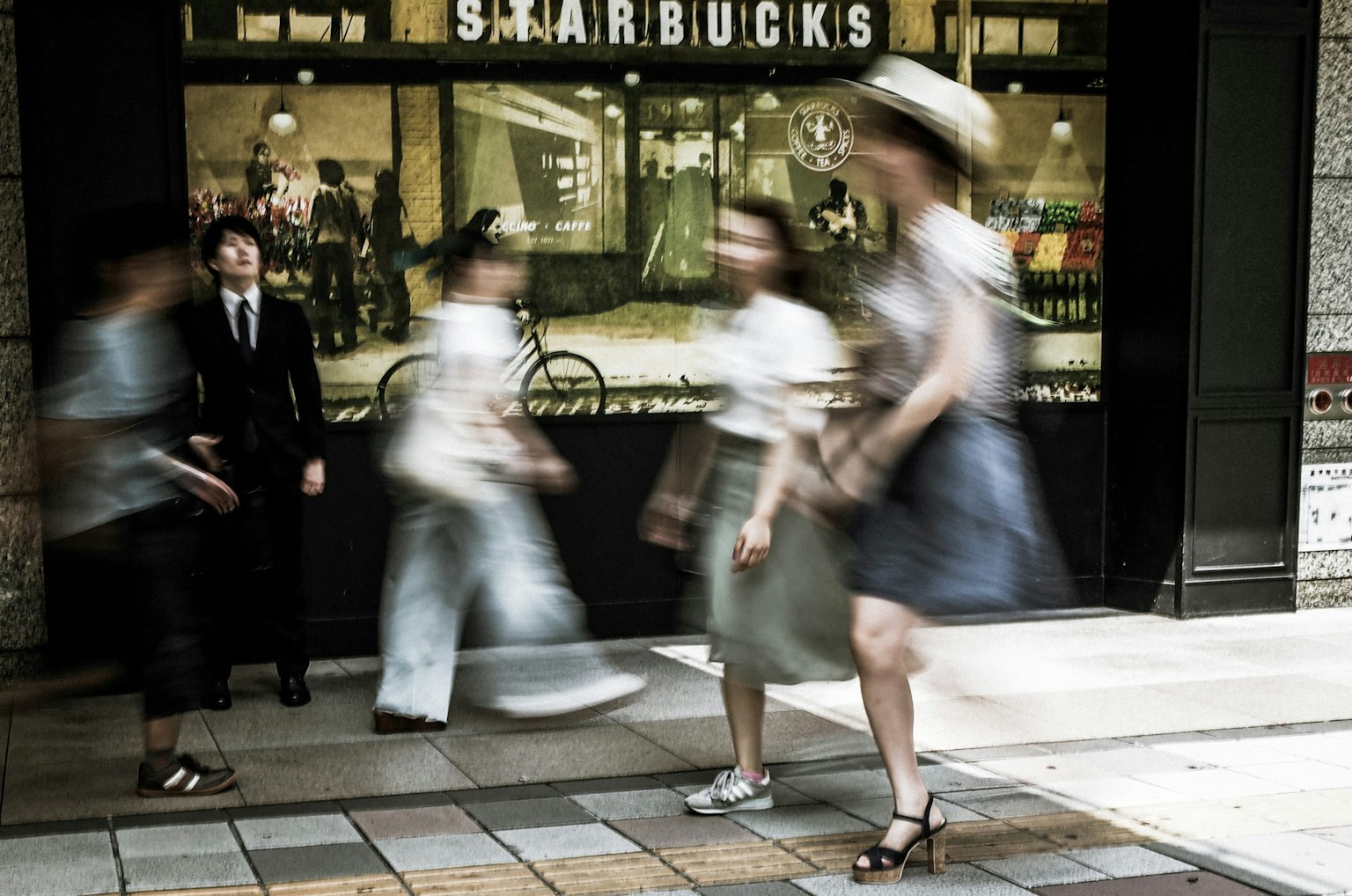 Escena de personas moviéndose frente a un café con un cartel de Starbucks