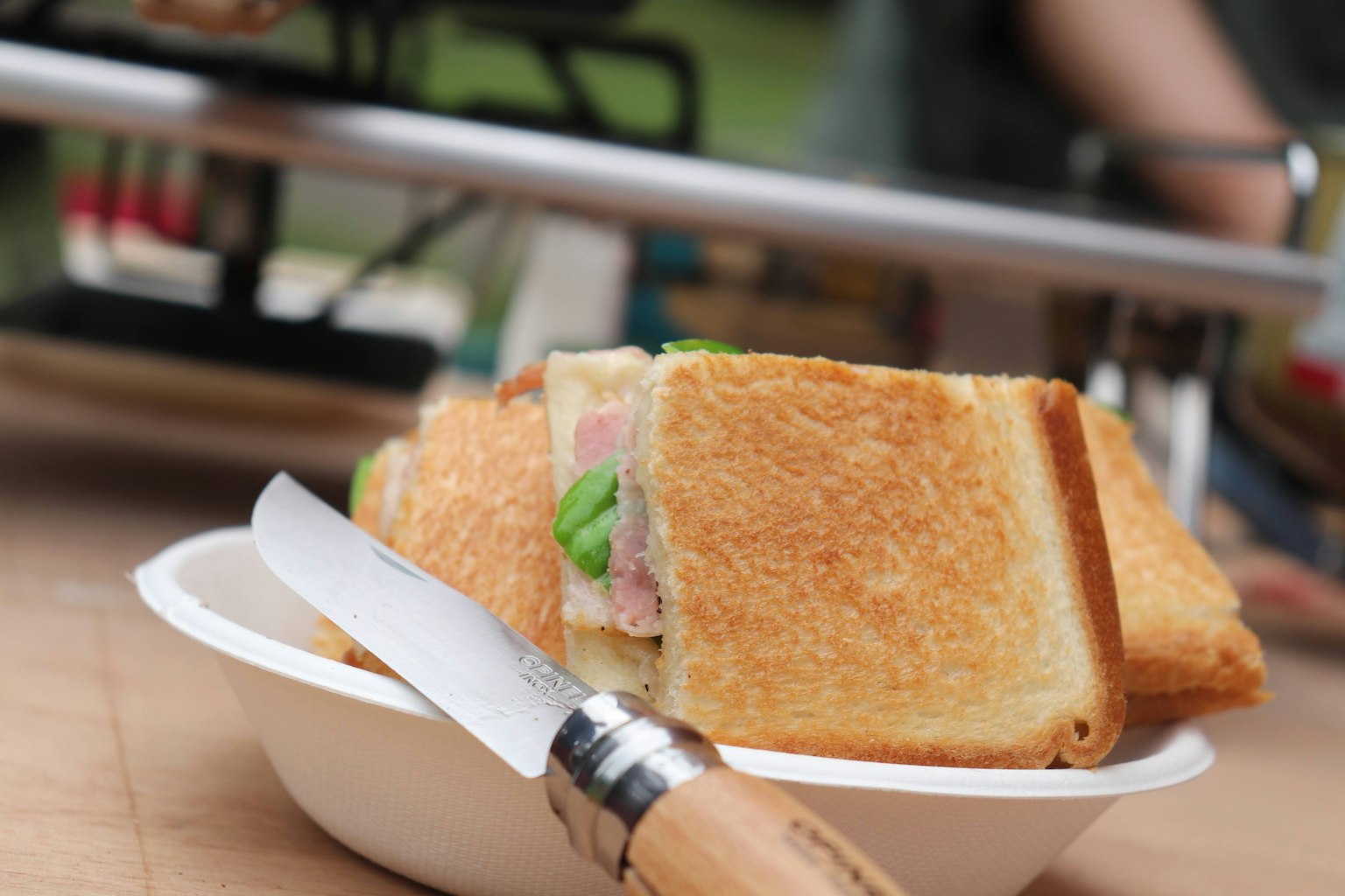 Sebuah sandwich di atas piring putih dengan pisau di sampingnya