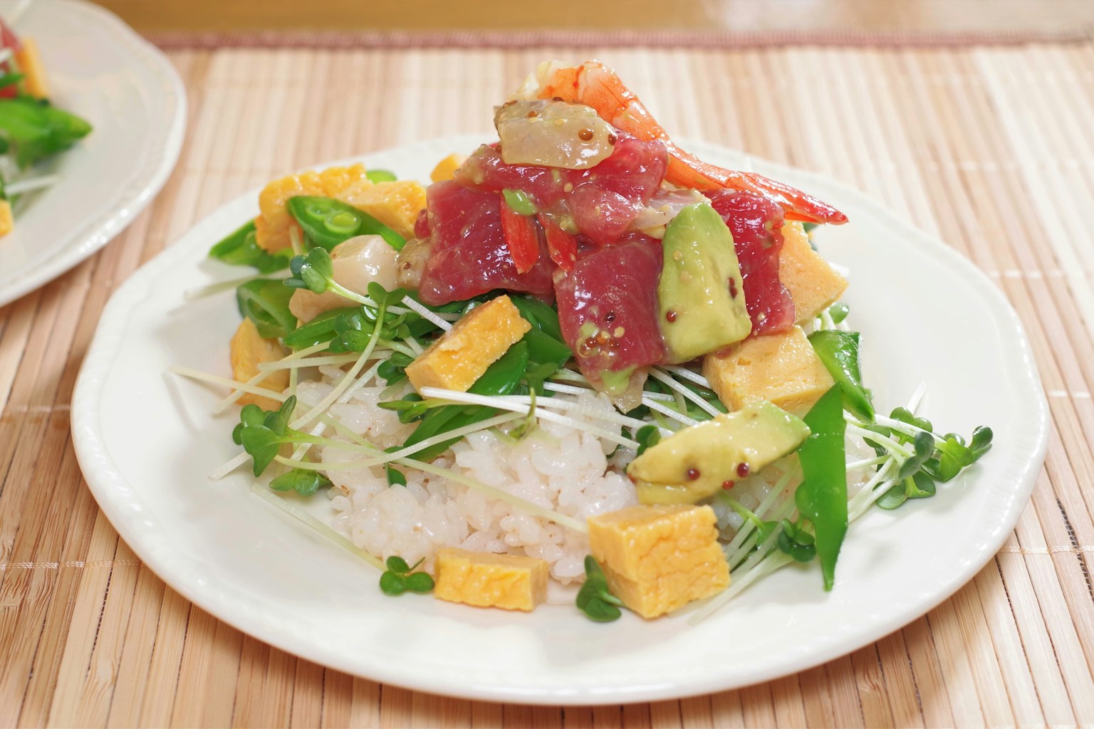 Một đĩa cơm được phủ bằng sashimi tươi, bơ và rau củ bao gồm trứng