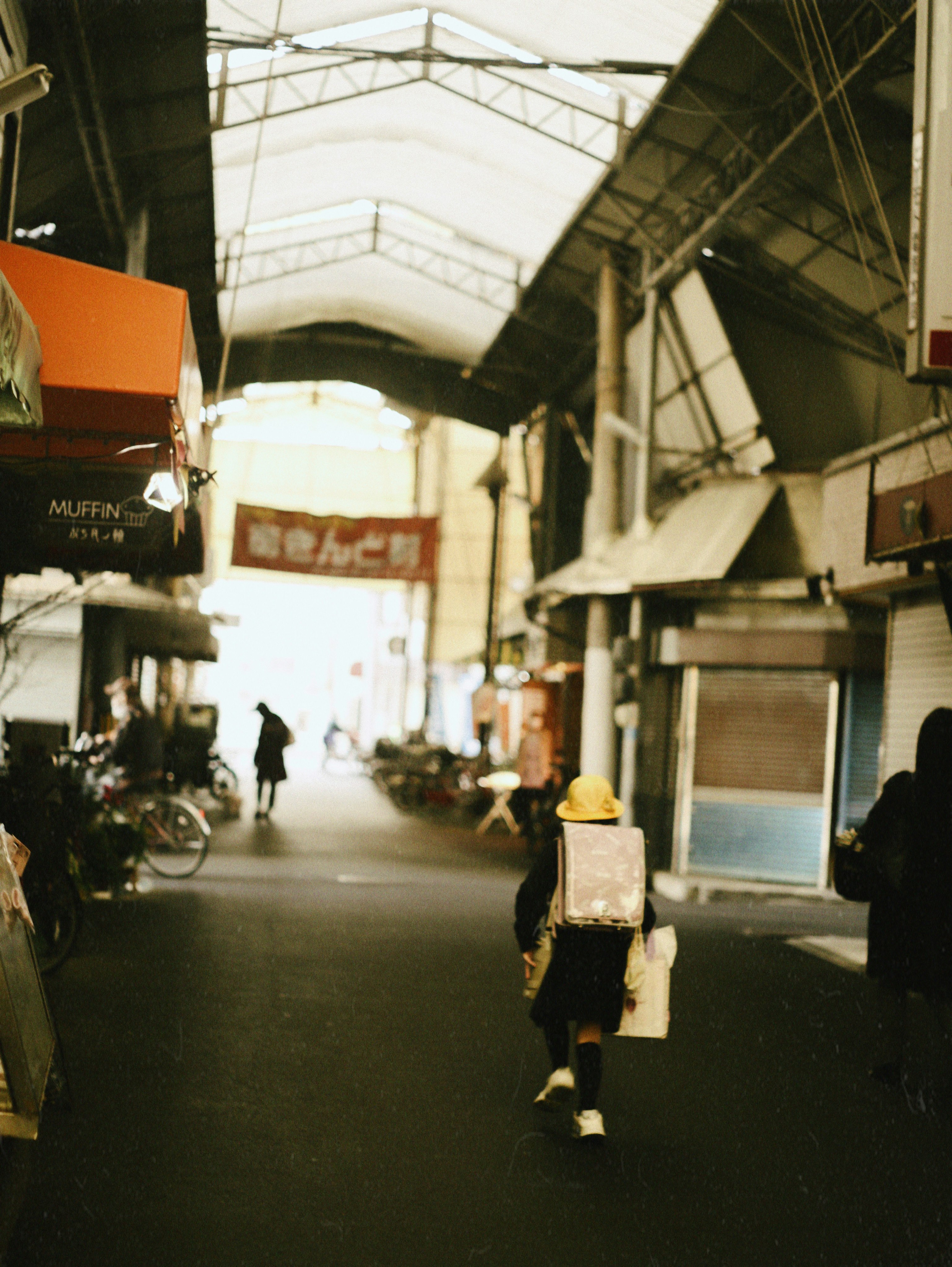 人が歩いている狭い商店街の風景 明るい出口が見える
