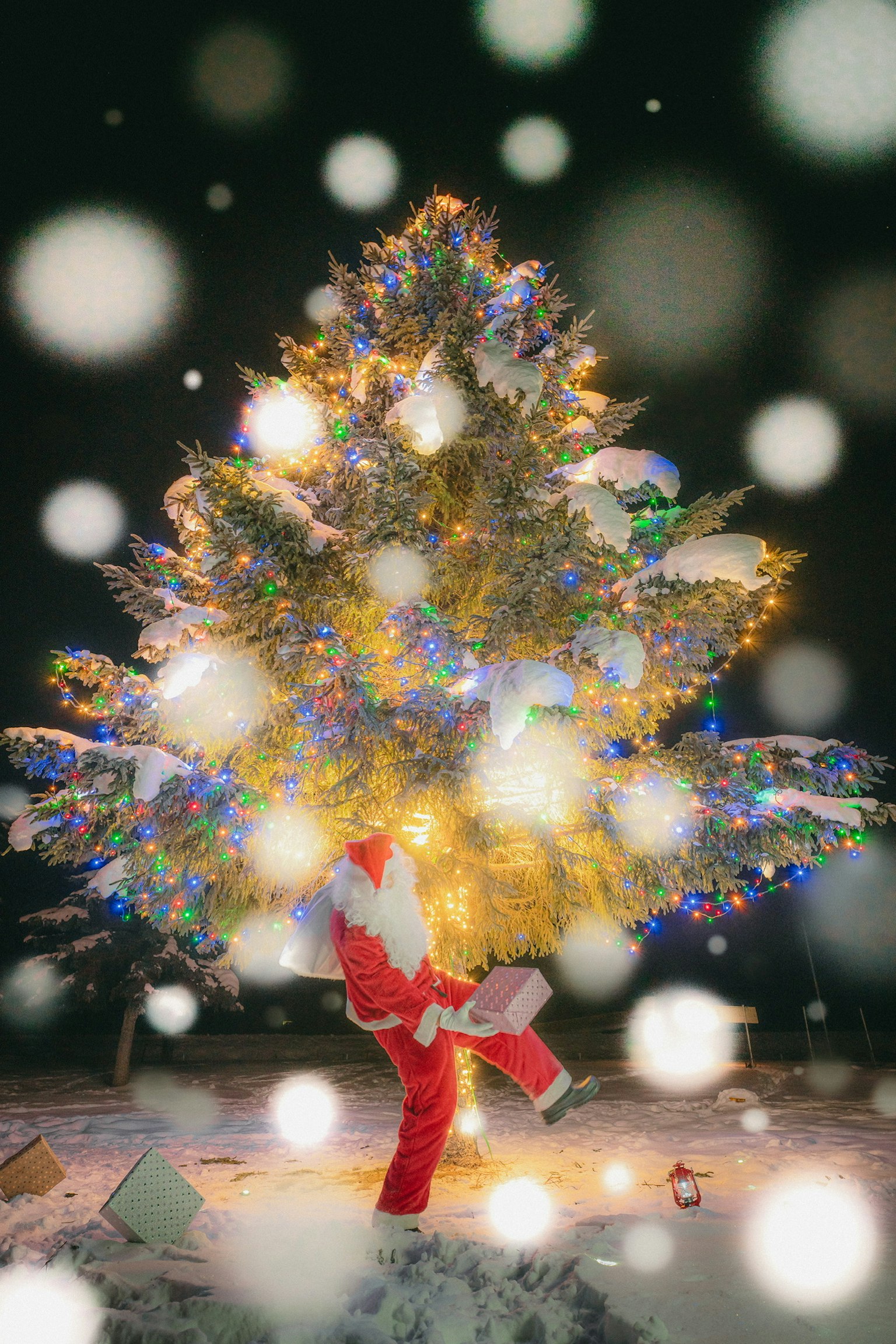 Père Noël debout dans la neige avec un sapin de Noël magnifiquement décoré