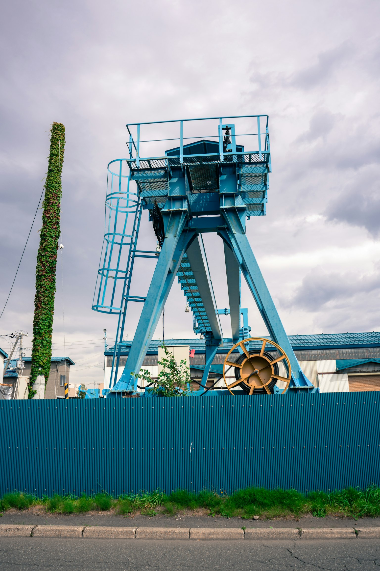 Blaue Industrieanlage mit Zaun im Hintergrund