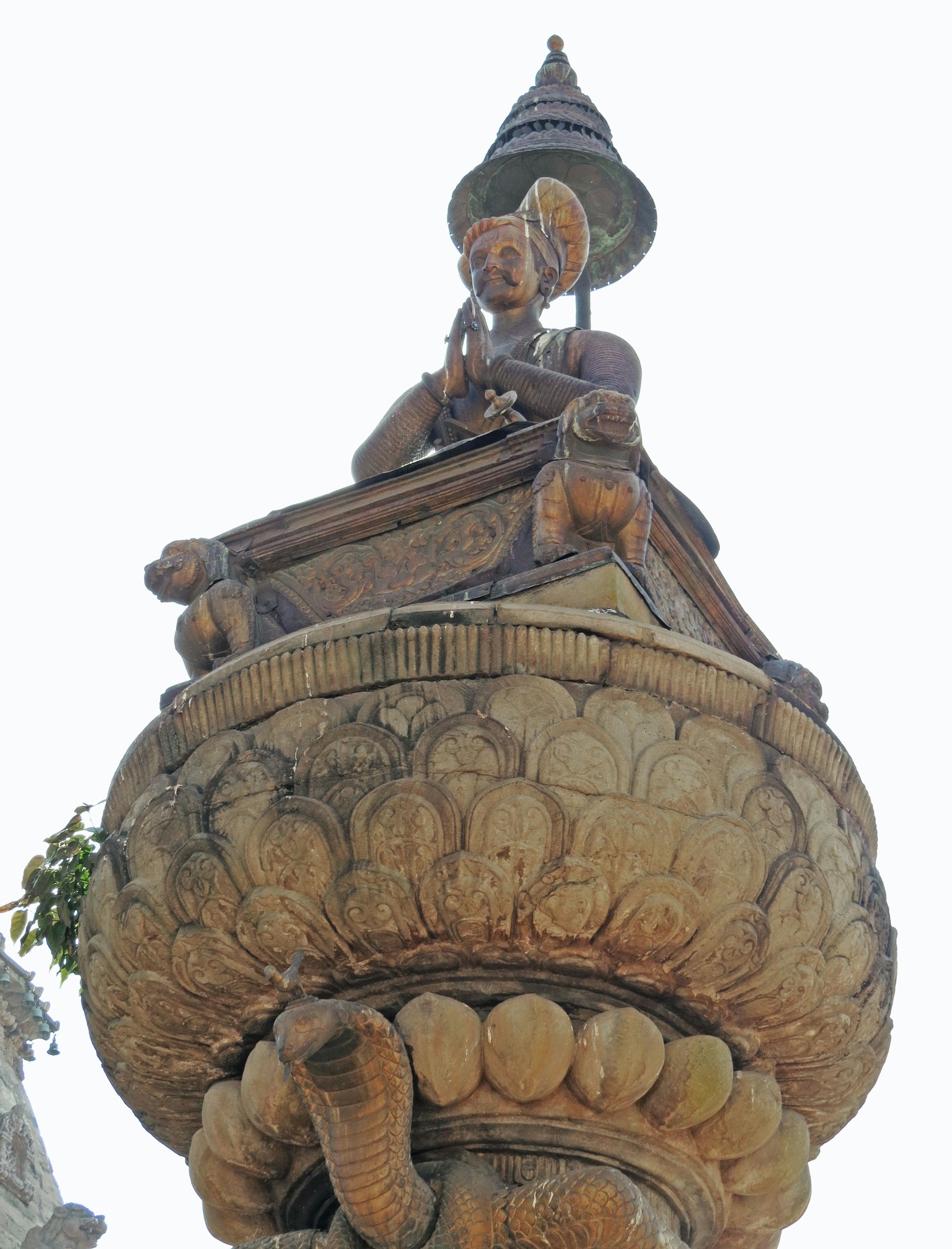 Une statue d'une personne sur une colonne décorative avec des sculptures complexes