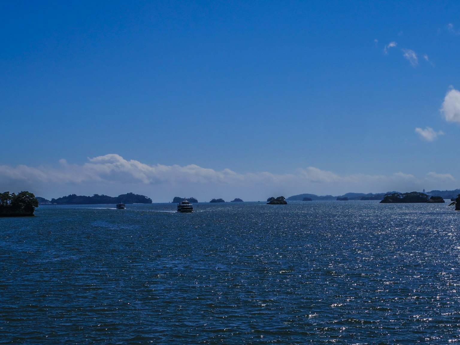 Pemandangan indah laut biru dengan perahu dan awan besar di langit