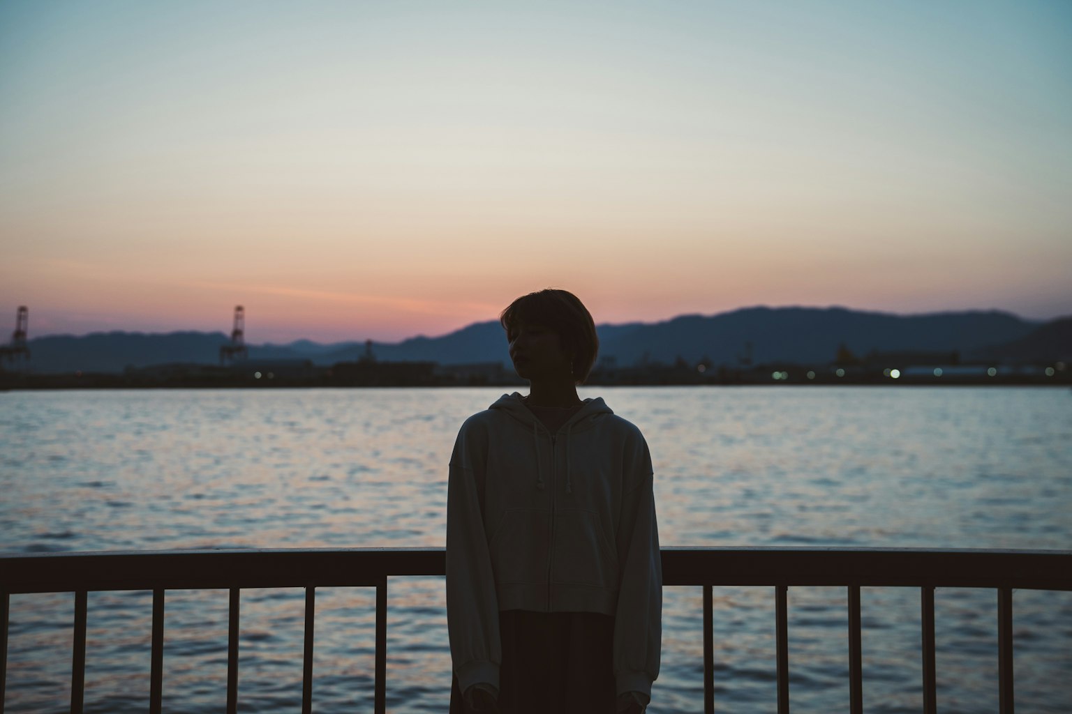 水邊站著的人物輪廓在日落時分