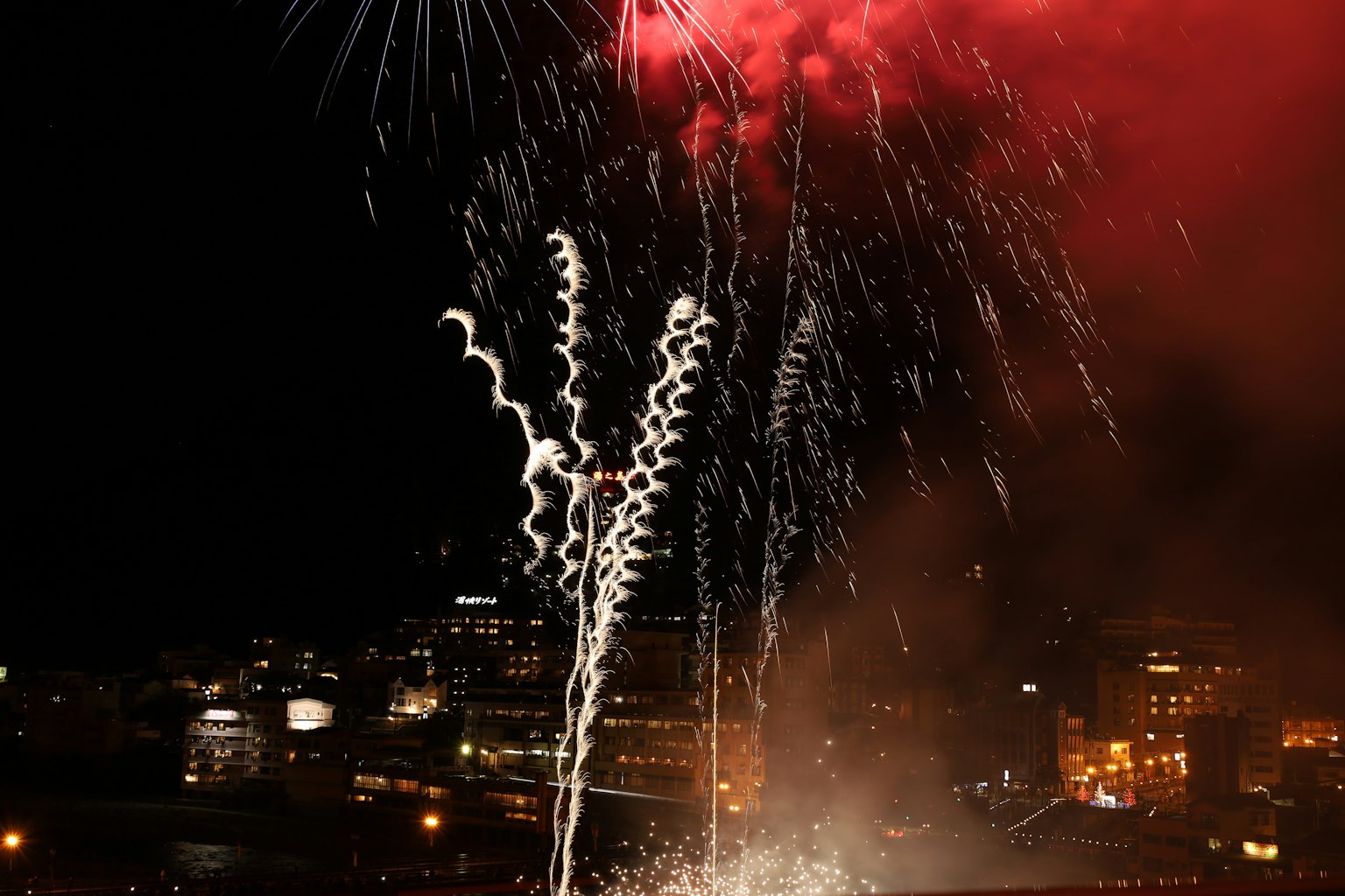 Fuochi d'artificio che esplodono nel cielo notturno sopra un paesaggio urbano