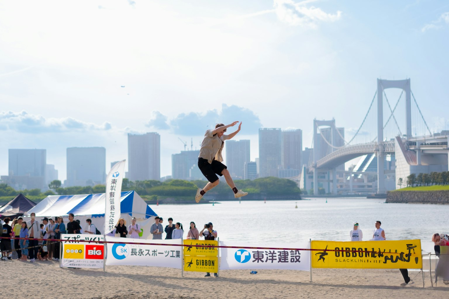 A man jumping on the beach with the Rainbow Bridge in the background