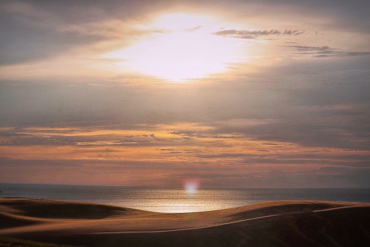 鳥取砂丘の夕暮れ前、砂丘と日本海に差す柔らかな光の情景