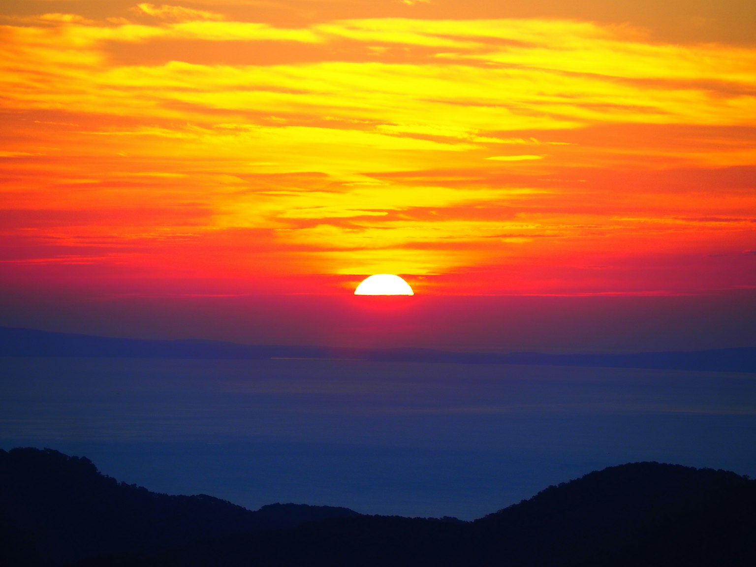 Impresionante atardecer sobre el océano con vibrantes tonos de naranja y amarillo
