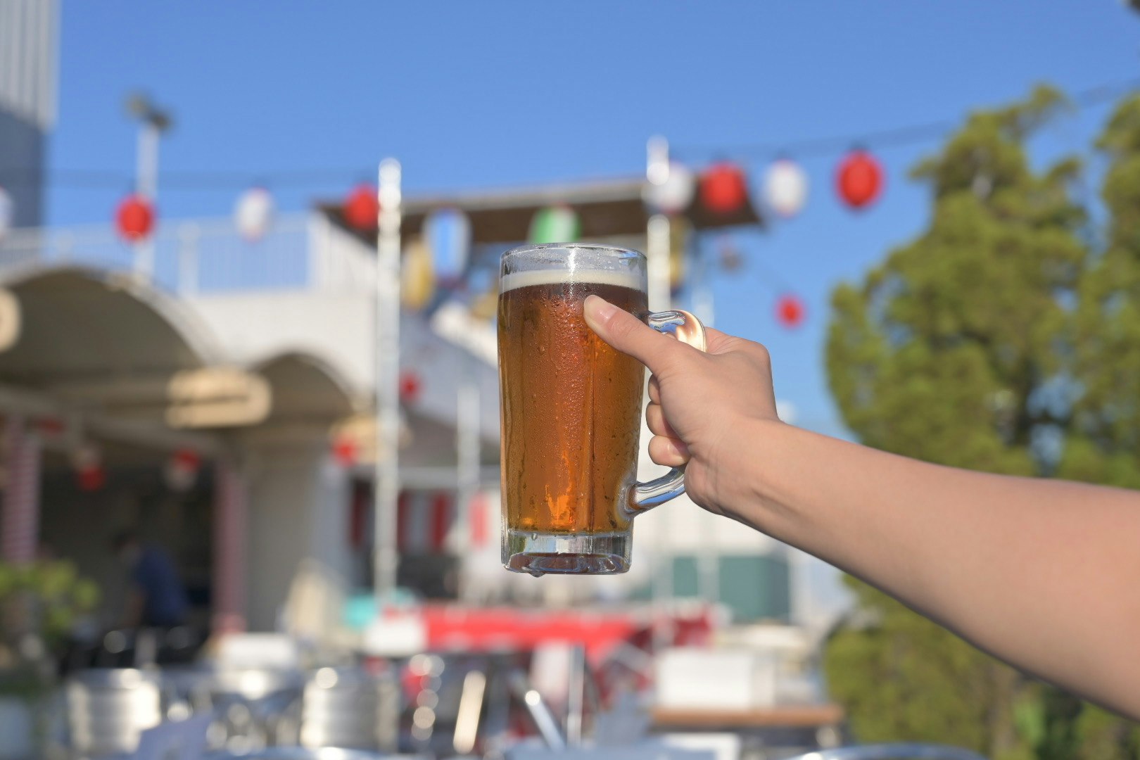 屋外のビアガーデンでビールを注いで乾杯する手