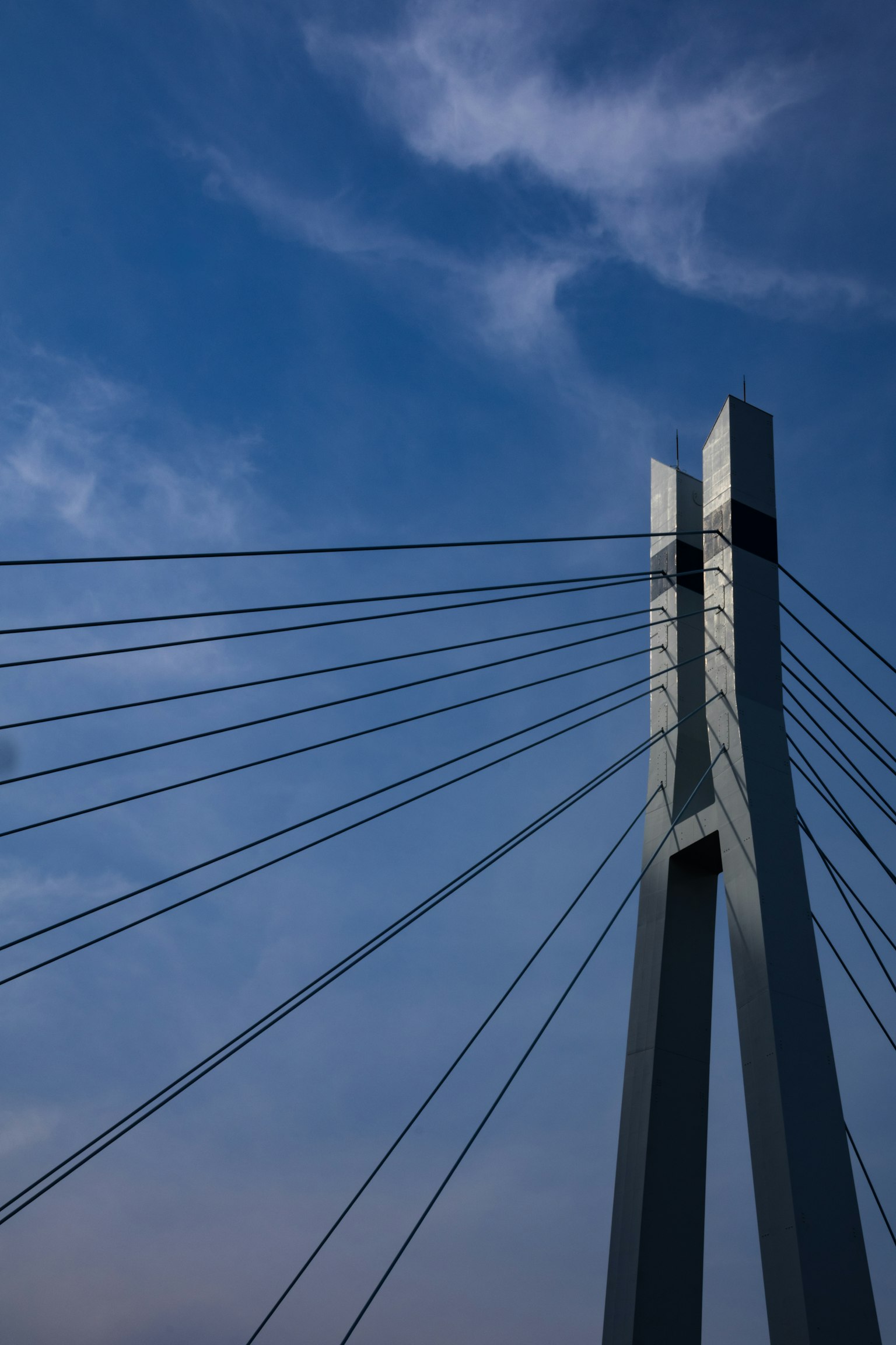 Torre di un ponte sospeso moderno con cavi contro un cielo blu