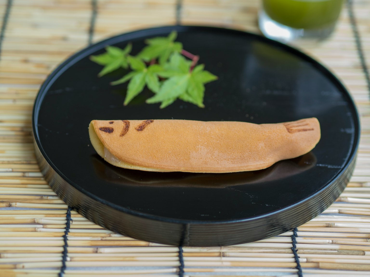 Kembang gula Jepang di piring hitam dengan daun hijau