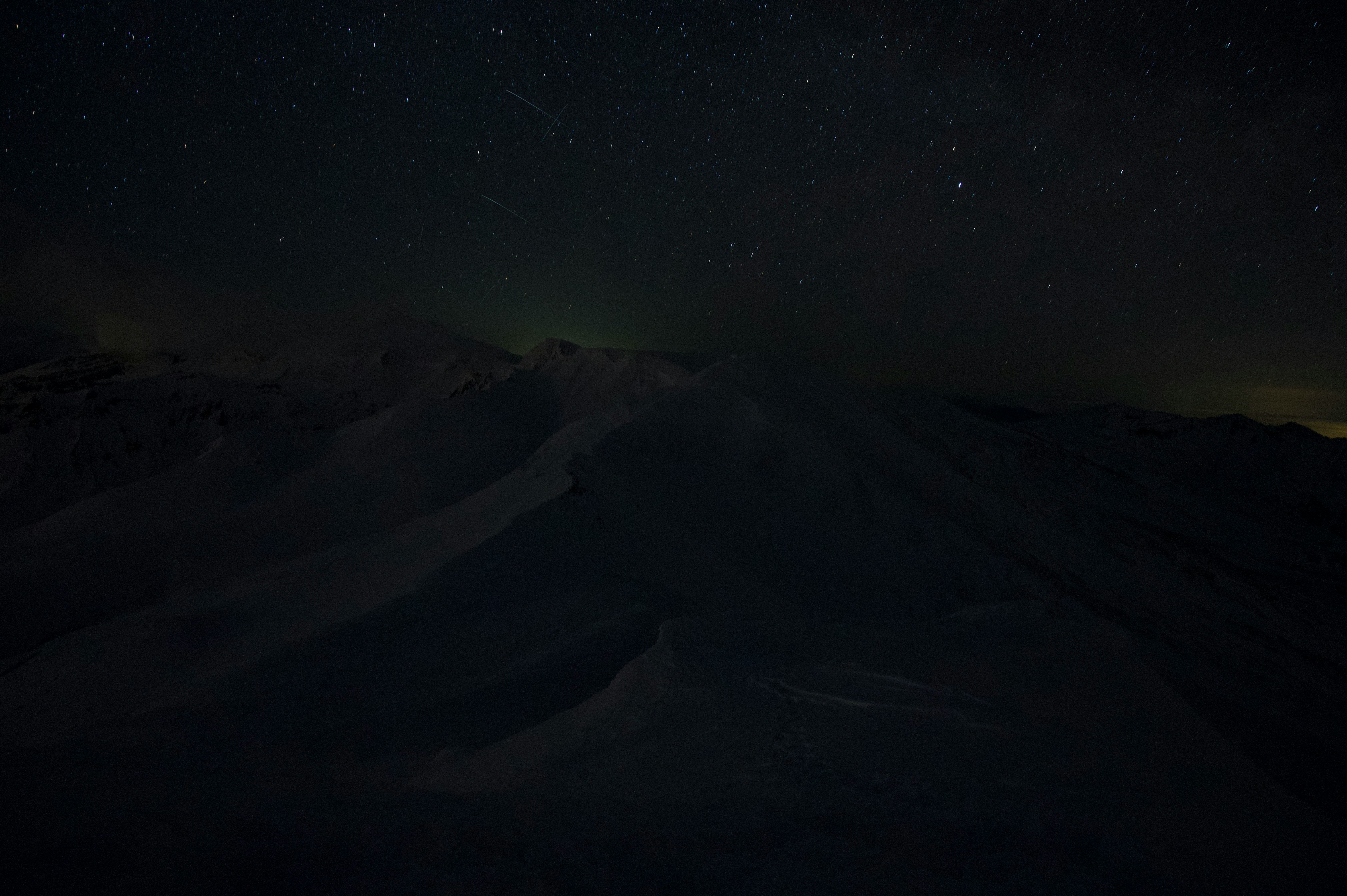 Night sky filled with stars above snow-covered mountains