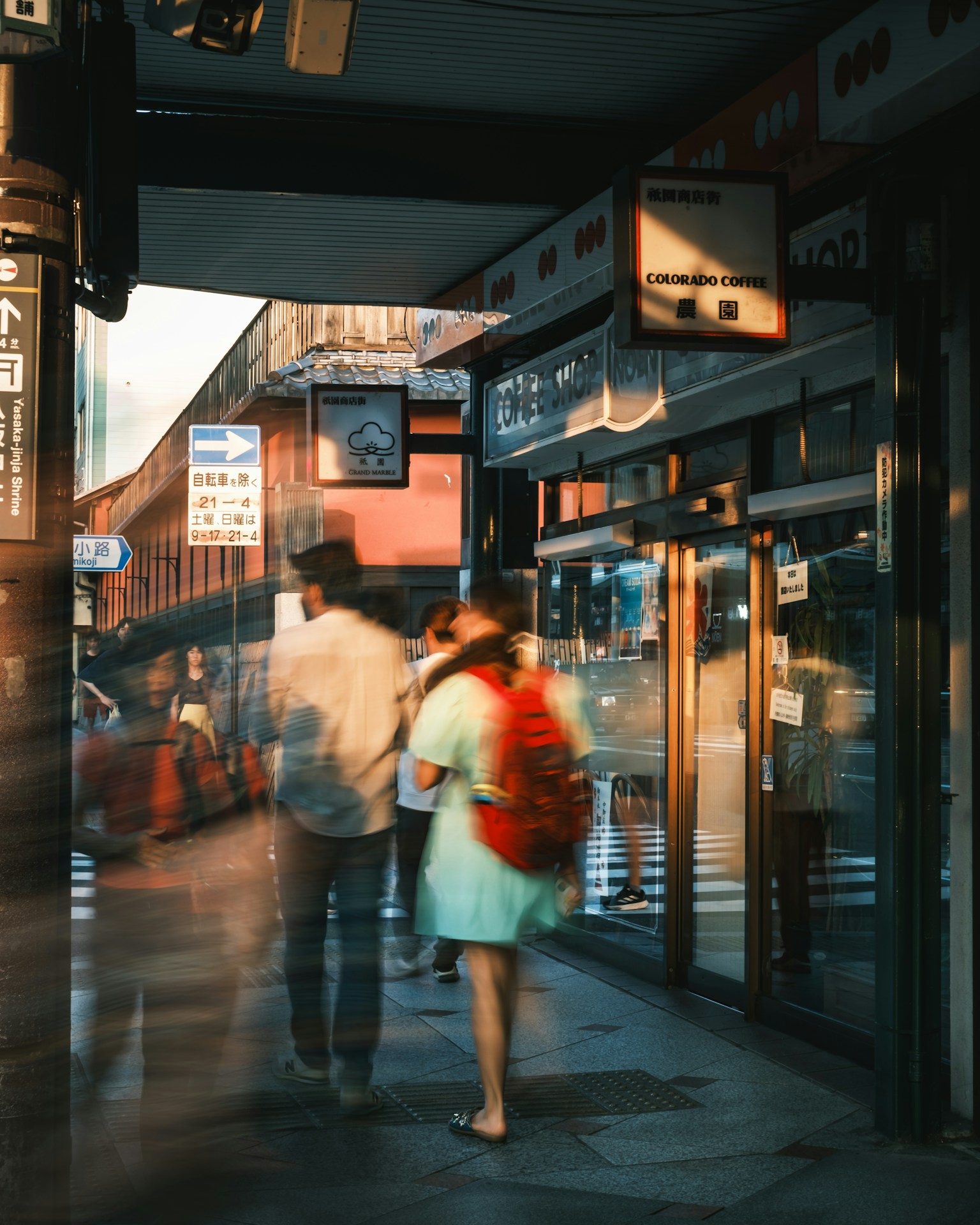 Des gens marchant dans une scène urbaine avec une lumière du soir illuminant une zone commerciale