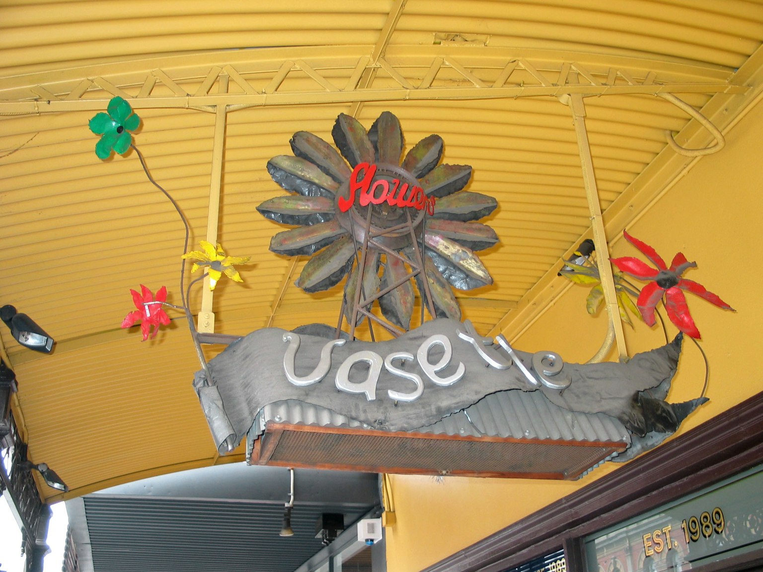 Cartel adornado con flores coloridas bajo un toldo amarillo