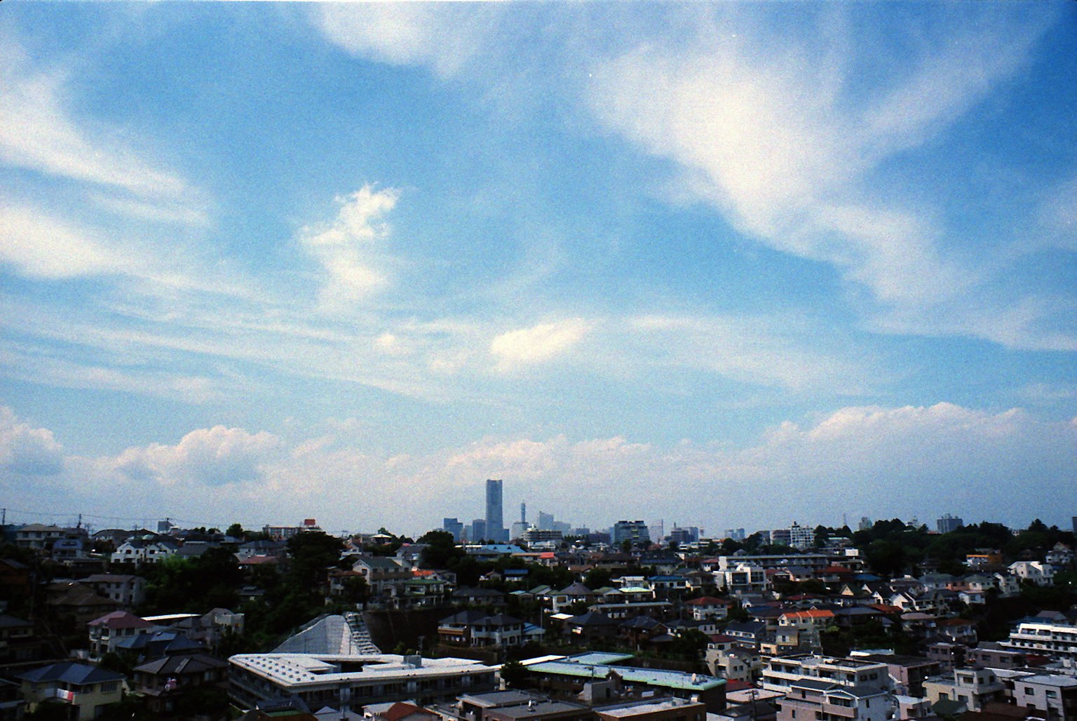Cityscape featuring blue sky and clouds with buildings and residential areas