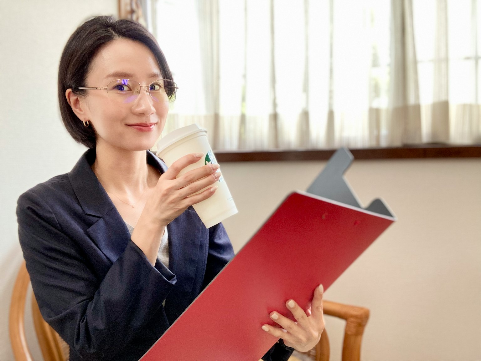 Wanita memegang folder merah dan cangkir kopi di lingkungan kantor