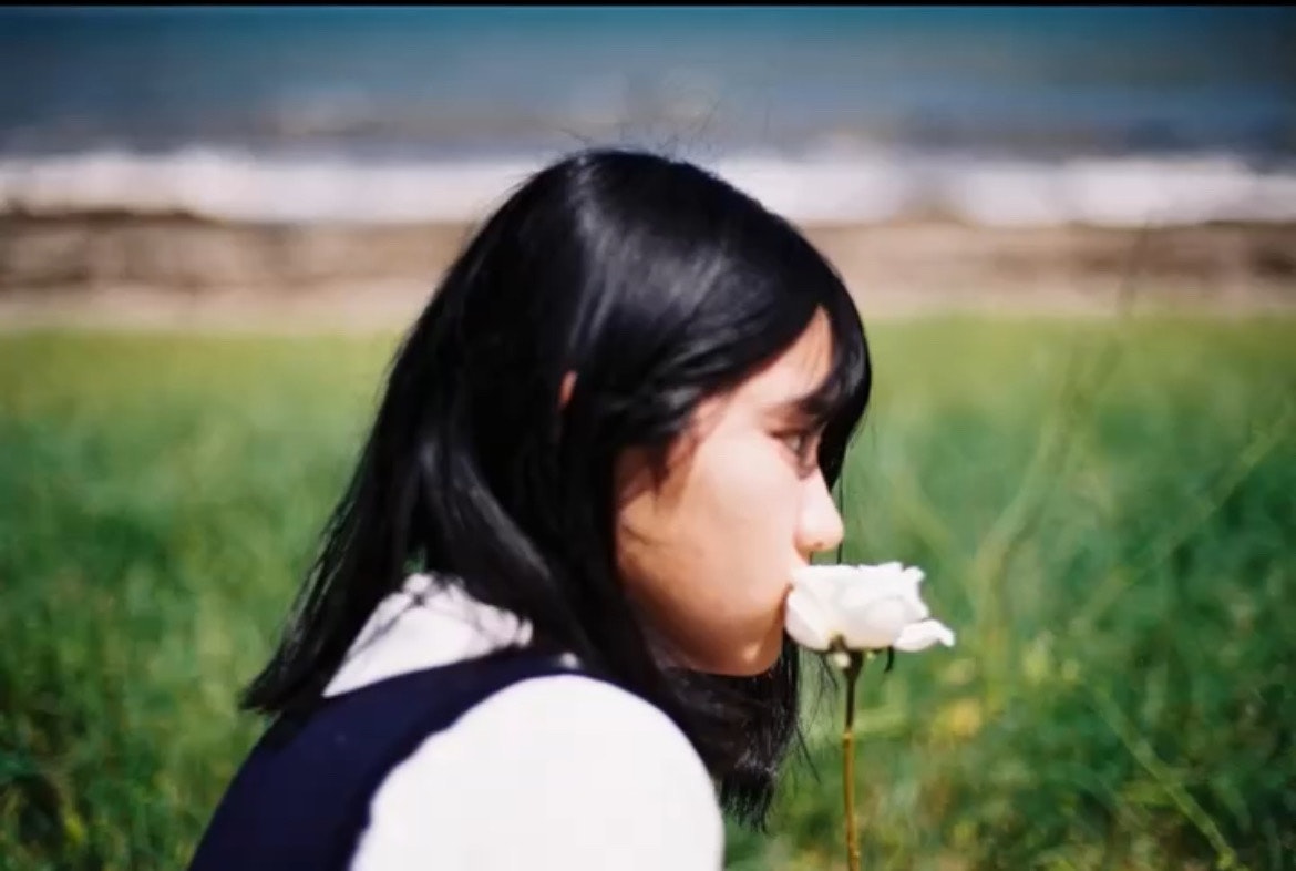 草原で花を見つめる女性